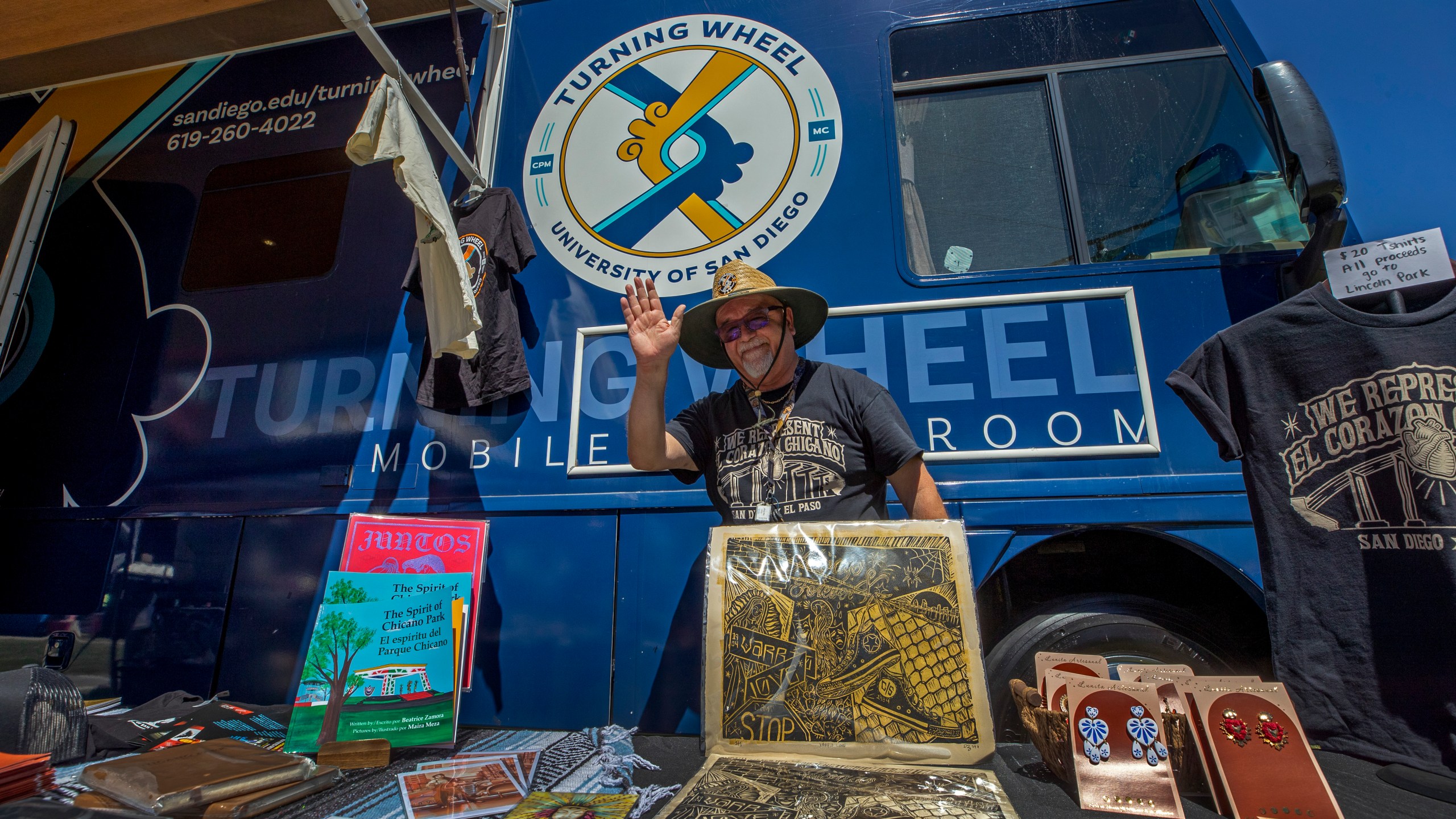 University of San Diego professor Alberto Lopez Pulido waves from his mobile classroom bus while attending a lowrider exhibition for the 20th anniversary of Lincoln Park in El Paso, Texas, Sunday, Sept. 22, 2024. (AP Photo/Andrés Leighton)