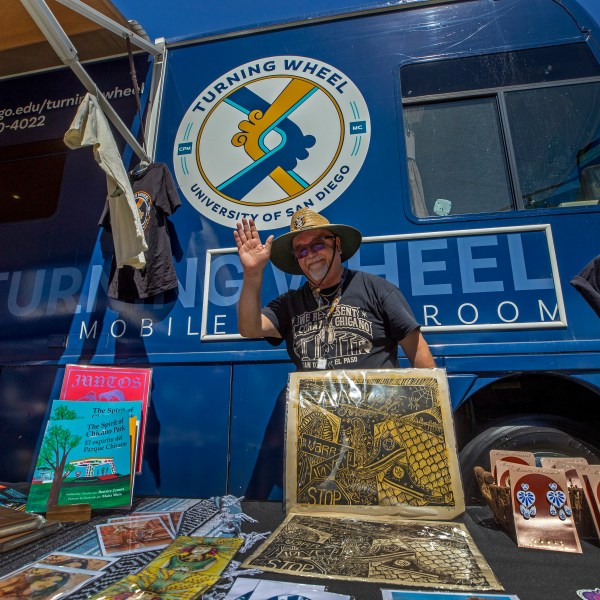 University of San Diego professor Alberto Lopez Pulido waves from his mobile classroom bus while attending a lowrider exhibition for the 20th anniversary of Lincoln Park in El Paso, Texas, Sunday, Sept. 22, 2024. (AP Photo/Andrés Leighton)