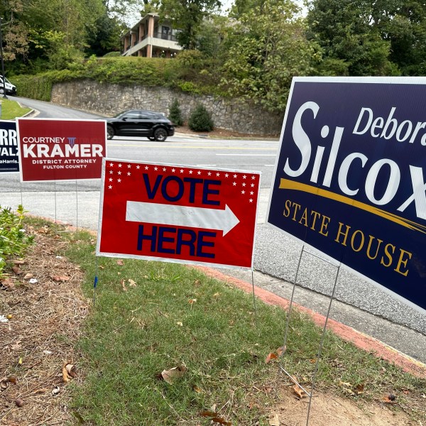 Signs entice voters in the Atlanta suburb of Sandy Springs, Ga., Tuesday, Oct. 15, 2024, the first day of early in-person voting in Georgia. (AP Photo/Jeff Amy)