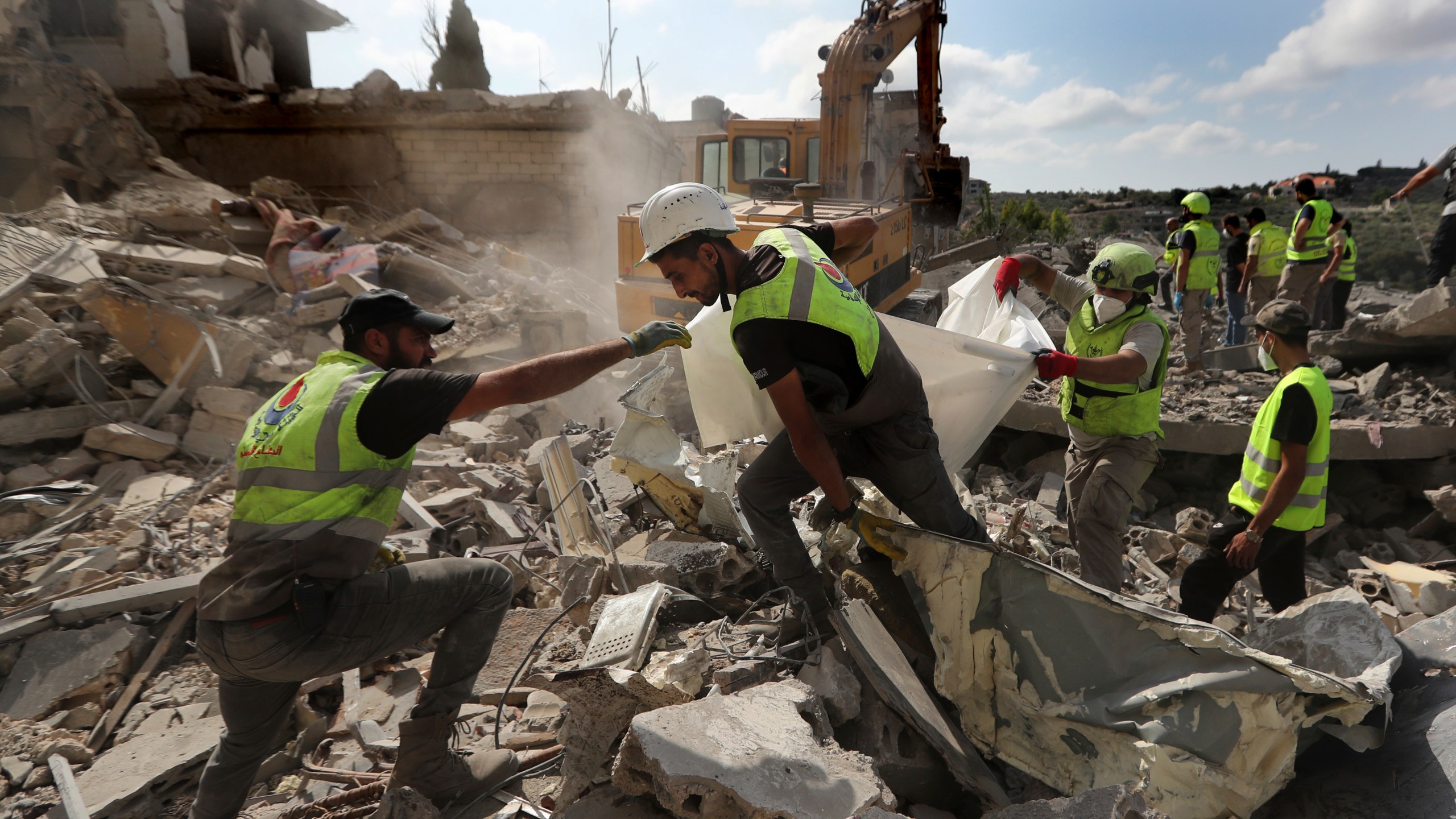 Rescue workers carry remains of people at at site that was hit by Israeli airstrikes in Qana village, south Lebanon, Wednesday, Oct. 16, 2024. (AP Photo/Mohammed Zaatari)