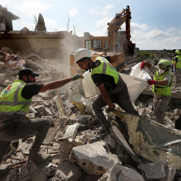 Rescue workers carry remains of people at at site that was hit by Israeli airstrikes in Qana village, south Lebanon, Wednesday, Oct. 16, 2024. (AP Photo/Mohammed Zaatari)