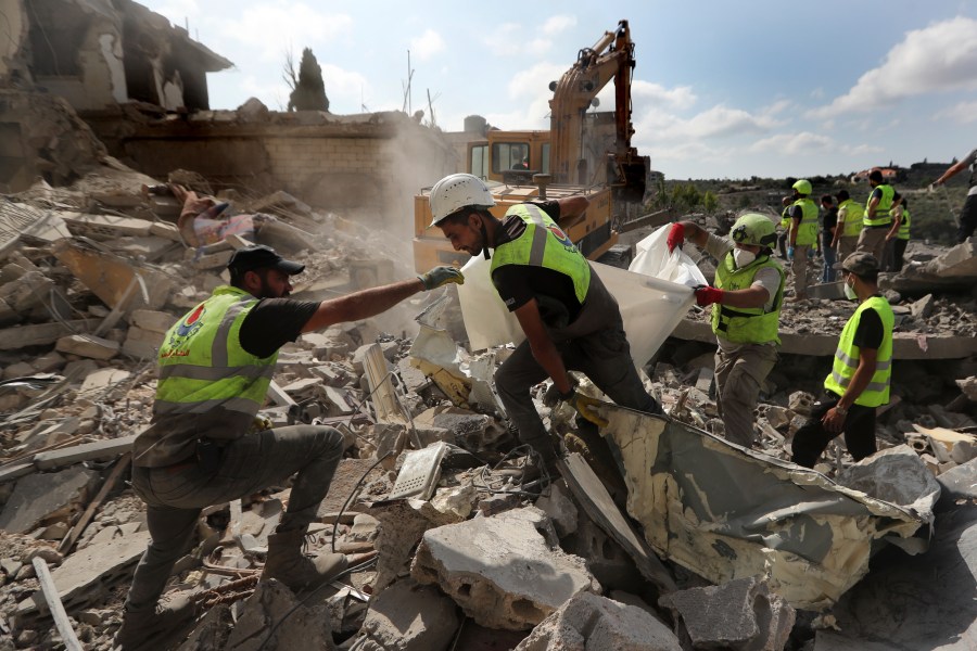 Rescue workers carry remains of people at at site that was hit by Israeli airstrikes in Qana village, south Lebanon, Wednesday, Oct. 16, 2024. (AP Photo/Mohammed Zaatari)