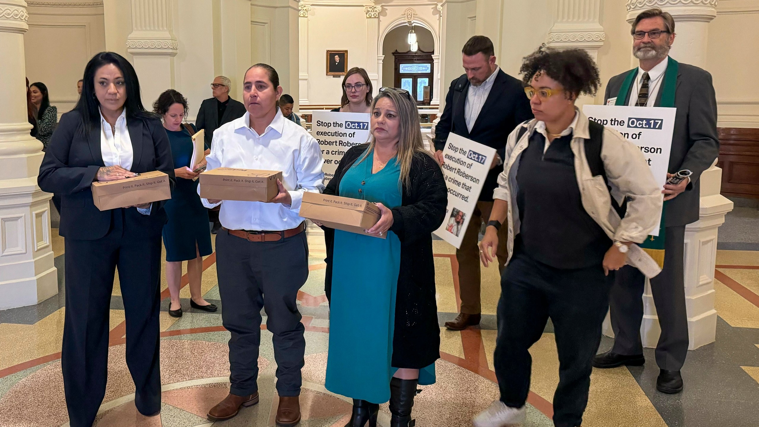 Casandra Rivera, left, Anna Vasquez, second from left, and Elizabeth Ramirez, center, of the "San Antonio 4" group, hold boxes with petitions being delivered in the Texas State capitol for Texas Gov. Greg Abbott seeking the pardoning of Robert Roberson's execution, Wednesday, Oct. 16, 2024 in Austin, Texas. Roberson, 57, is scheduled to receive a lethal injection on Oct. 17, for the 2002 killing of his 2-year-old daughter, Nikki Curtis, in the East Texas city of Palestine. Roberson has long proclaimed his innocence. (AP Photo/Nadia Lathan)