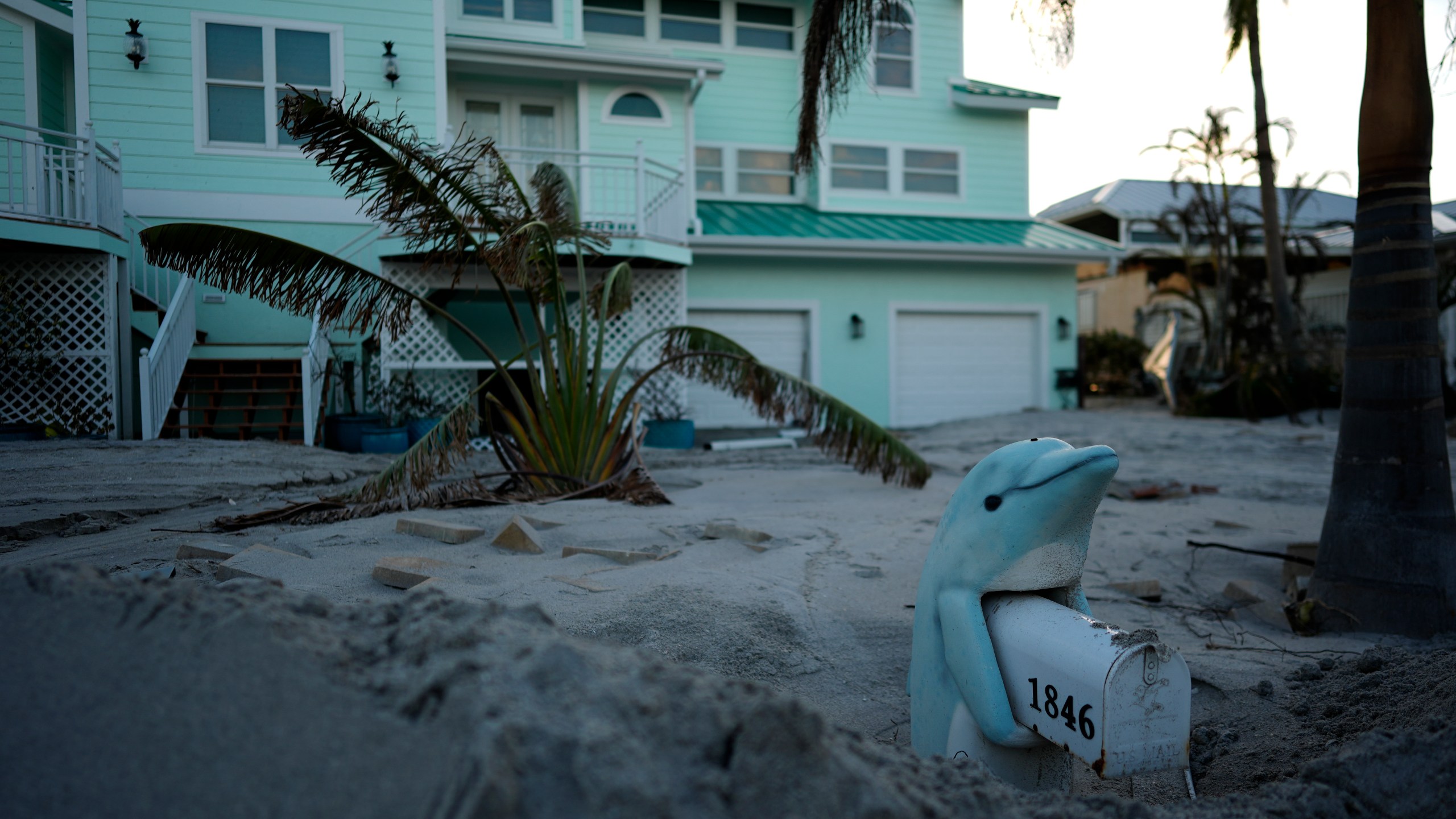 A porpoise mailbox stand is partially buried in feet of sand on Manasota Key, Fla., following Hurricane Milton, Saturday, Oct. 12, 2024. (AP Photo/Rebecca Blackwell)