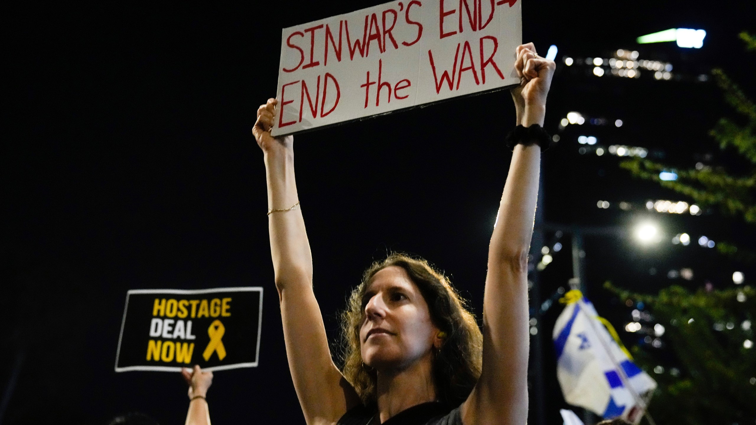 A demonstrator holds a sign about the killing of Hamas leader Yahya Sinwar during a protest calling for a cease-fire deal and the immediate release of hostages held by Hamas on Thursday, Oct. 17, 2024, in Tel Aviv, Israel. (AP Photo/Ariel Schalit)