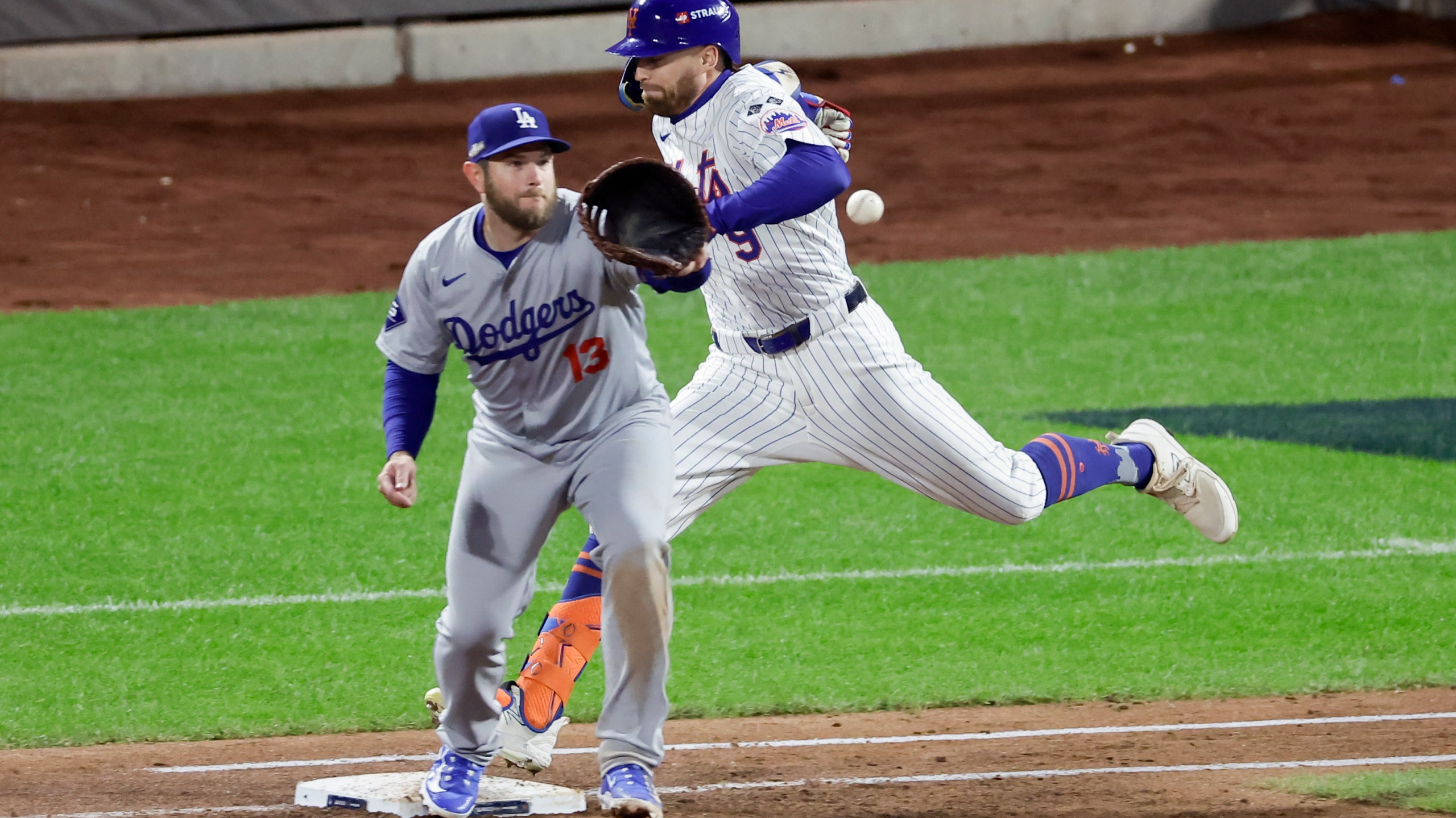 New York Mets' Brandon Nimmo is safe at first past Los Angeles Dodgers first baseman Max Muncy during the third inning in Game 4 of a baseball NL Championship Series, Thursday, Oct. 17, 2024, in New York. (AP Photo/Adam Hunger)