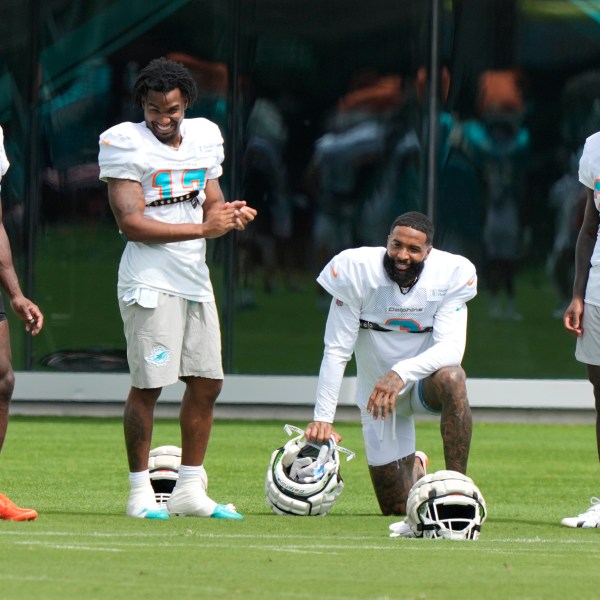 Miami Dolphins wide receiver Odell Beckham Jr., second from right, talks with wide receiver Tyreek Hill (10), wide receiver Jaylen Waddle (17) and running back De'Von Achane (28) during practice at the NFL football team's training facility, Thursday, Oct. 3, 2024, in Miami Gardens, Fla. (AP Photo/Lynne Sladky)