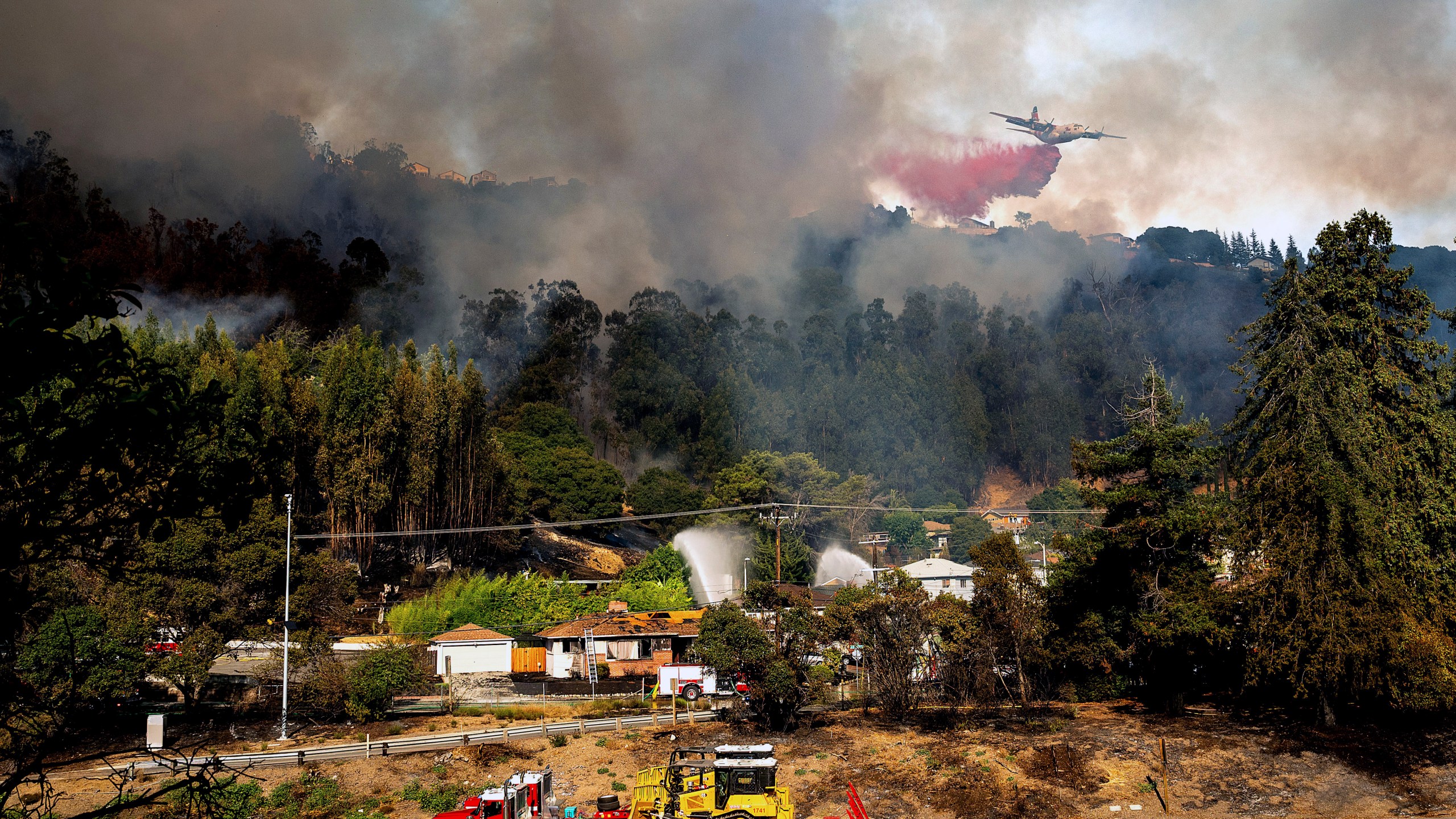 An air tanker drops retardant on a grass fire burning above Interstate 580 in Oakland, Calif., Friday, Oct. 18, 2024. (AP Photo/Noah Berger)