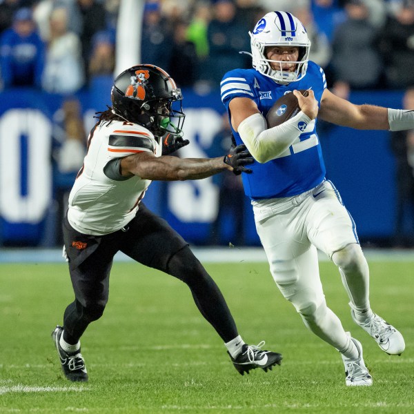 BYU quarterback Jake Retzlaff runs the ball ahead of Oklahoma State cornerback Korie Black in the second half of an NCAA college football game, Friday, Oct. 18, 2024, in Provo, Utah. (AP Photo/Spenser Heaps)