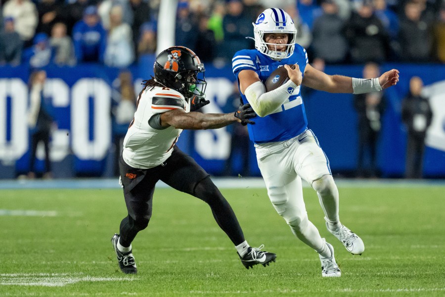 BYU quarterback Jake Retzlaff runs the ball ahead of Oklahoma State cornerback Korie Black in the second half of an NCAA college football game, Friday, Oct. 18, 2024, in Provo, Utah. (AP Photo/Spenser Heaps)