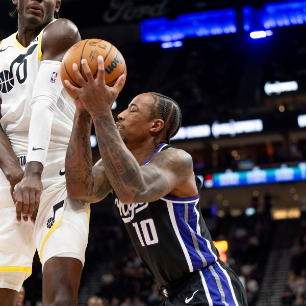 Utah Jazz forward Taylor Hendricks (0) draws the foul charge as Sacramento Kings forward DeMar DeRozan (10) shoots in the first half of an NBA preseason basketball game, Tuesday, Oct. 15, 2024, in Salt Lake City. (AP Photo/Spenser Heaps)