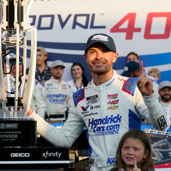 Kyle Larson poses with the trophy with his daughter Audrey, 6, after winning a NASCAR Cup Series auto race at Charlotte Motor Speedway in Concord, N.C., Sunday, Oct. 13, 2024. (AP Photo/Chuck Burton)