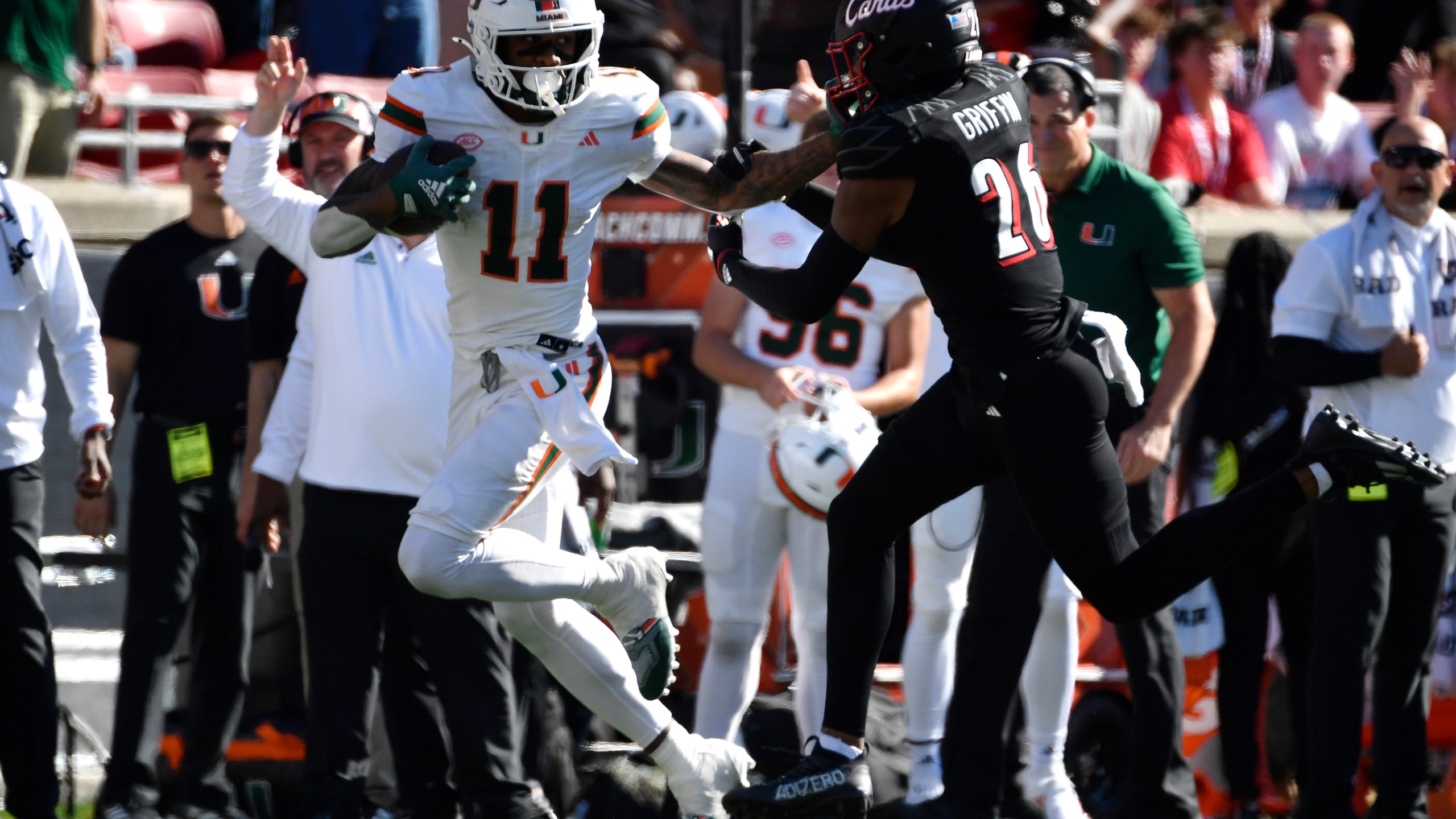 Miami wide receiver Samuel Brown (11) stiff arms Louisville defensive back M.J. Griffin (26) during the second half of an NCAA college football game in Louisville, Ky., Saturday, Oct. 19, 2024. Miami won 52-45. (AP Photo/Timothy D. Easley)