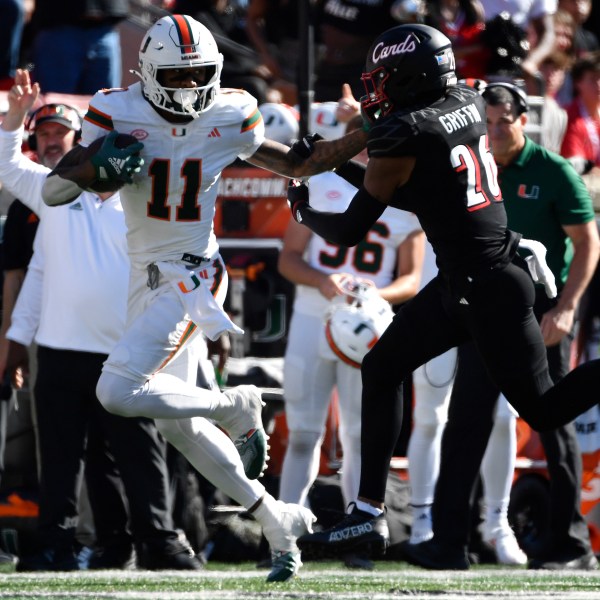 Miami wide receiver Samuel Brown (11) stiff arms Louisville defensive back M.J. Griffin (26) during the second half of an NCAA college football game in Louisville, Ky., Saturday, Oct. 19, 2024. Miami won 52-45. (AP Photo/Timothy D. Easley)