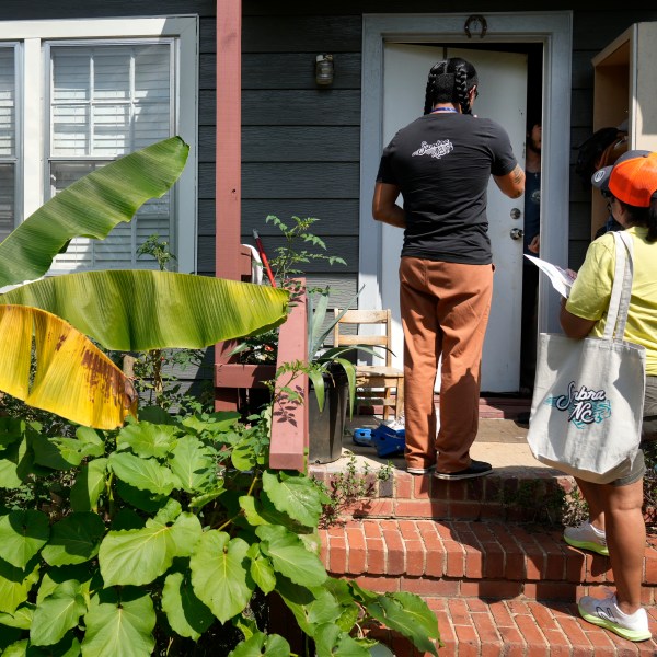 Salvador Fonseca, left, and Elena Jimenez talk to a homeowner during a voter engagement event for the Latino community in Greensboro, N.C., Saturday, Sept. 21, 2024. (AP Photo/Chuck Burton)