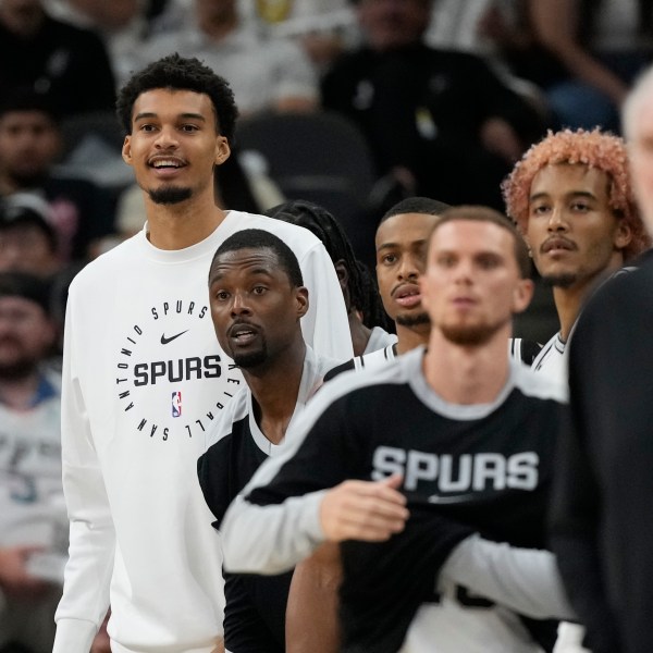 San Antonio Spurs center Victor Wembanyama, left, watches from the bench during the second half of a preseason NBA basketball game against the Oklahoma City Thunder in San Antonio, Monday, Oct. 7, 2024. (AP Photo/Eric Gay)