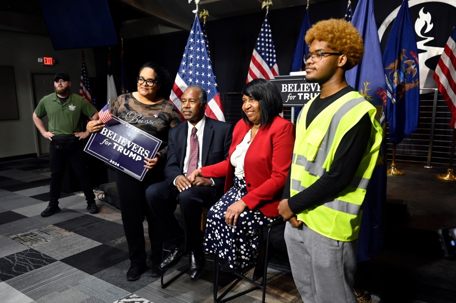 Ben Carson, center, and his wife Candy Carson, right center, pose for a photo with Tiffany King, second from left, and her son, Nehemiah King, right, following Carson's address to supporters of Republican presidential nominee former President Donald Trump, Saturday, Oct. 5, 2024, in Livonia, Mich. (AP Photo/Jose Juarez)