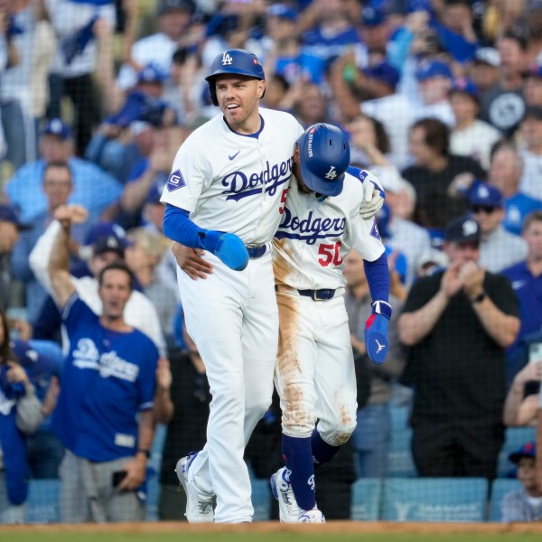 Los Angeles Dodgers' Freddie Freeman, left, and Mookie Betts celebrate after they scored on a single by Max Muncy during the first inning in Game 1 of a baseball NL Championship Series against the New York Mets, Sunday, Oct. 13, 2024, in Los Angeles. (AP Photo/Ashley Landis)