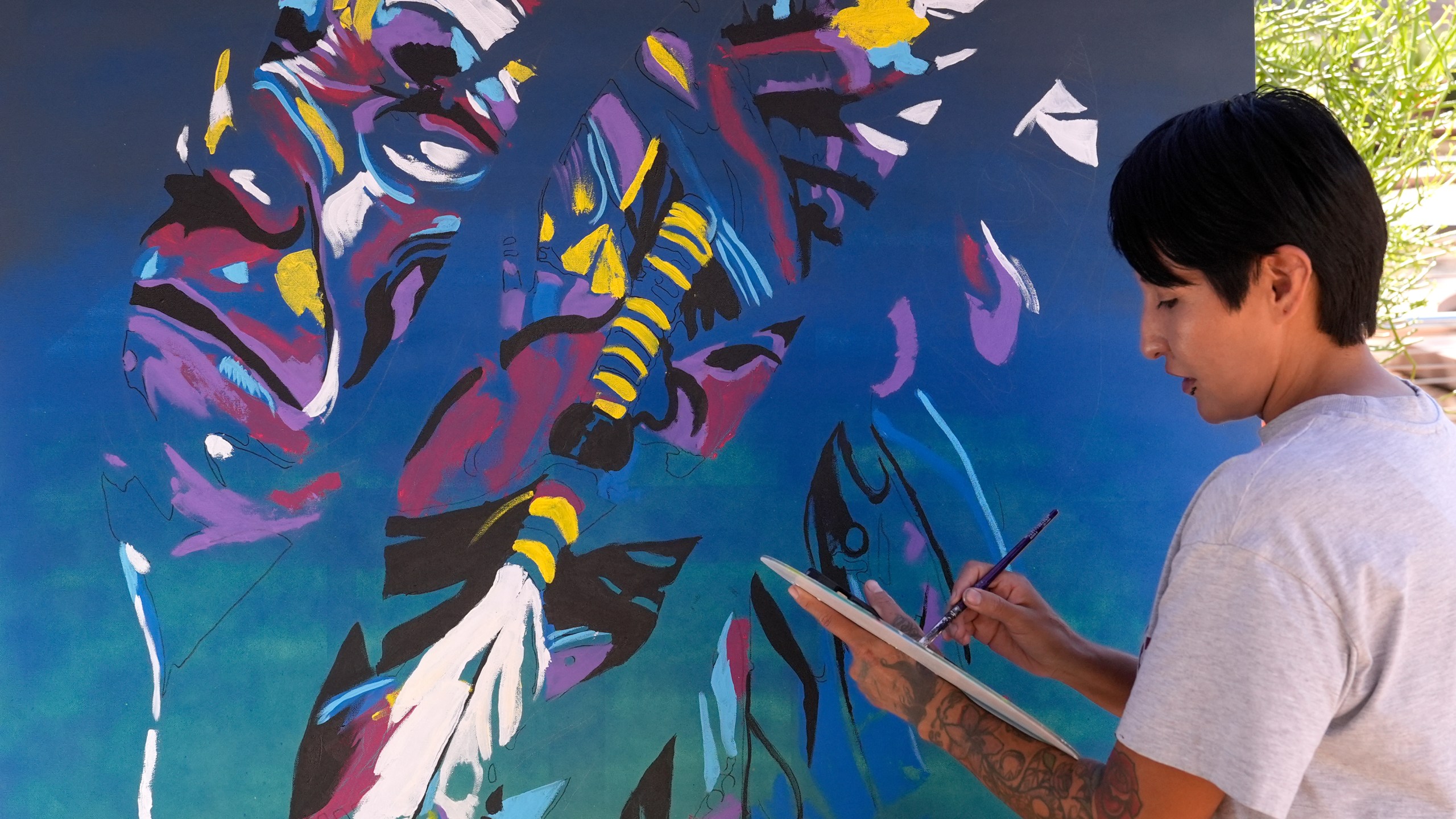 Artist Richelle Key works on the painting "Democracy Is Indigenous" during an Indigenous Peoples' Day event Monday, Oct. 14, 2024, in Phoenix. (AP Photo/Ross D. Franklin)