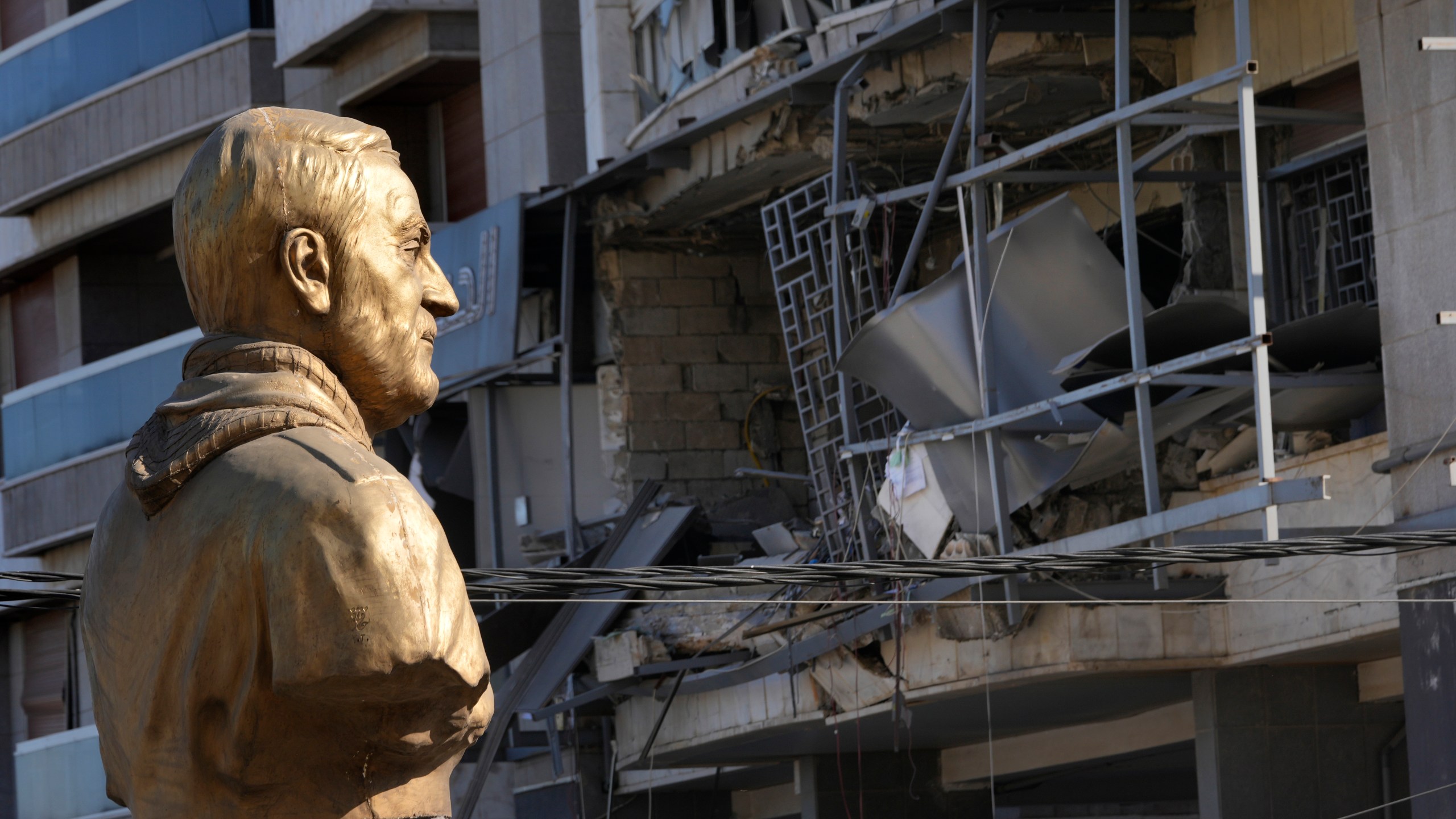 A bust of the late Iranian General Qassem Soleimani stands in front of a destroyed branch of the Hezbollah-run Qard al-Hassan, which was hit by an Israeli airstrike in Dahiyeh, Beirut, Lebanon, Monday, Oct. 21, 2024. (AP Photo/Hussein Malla)