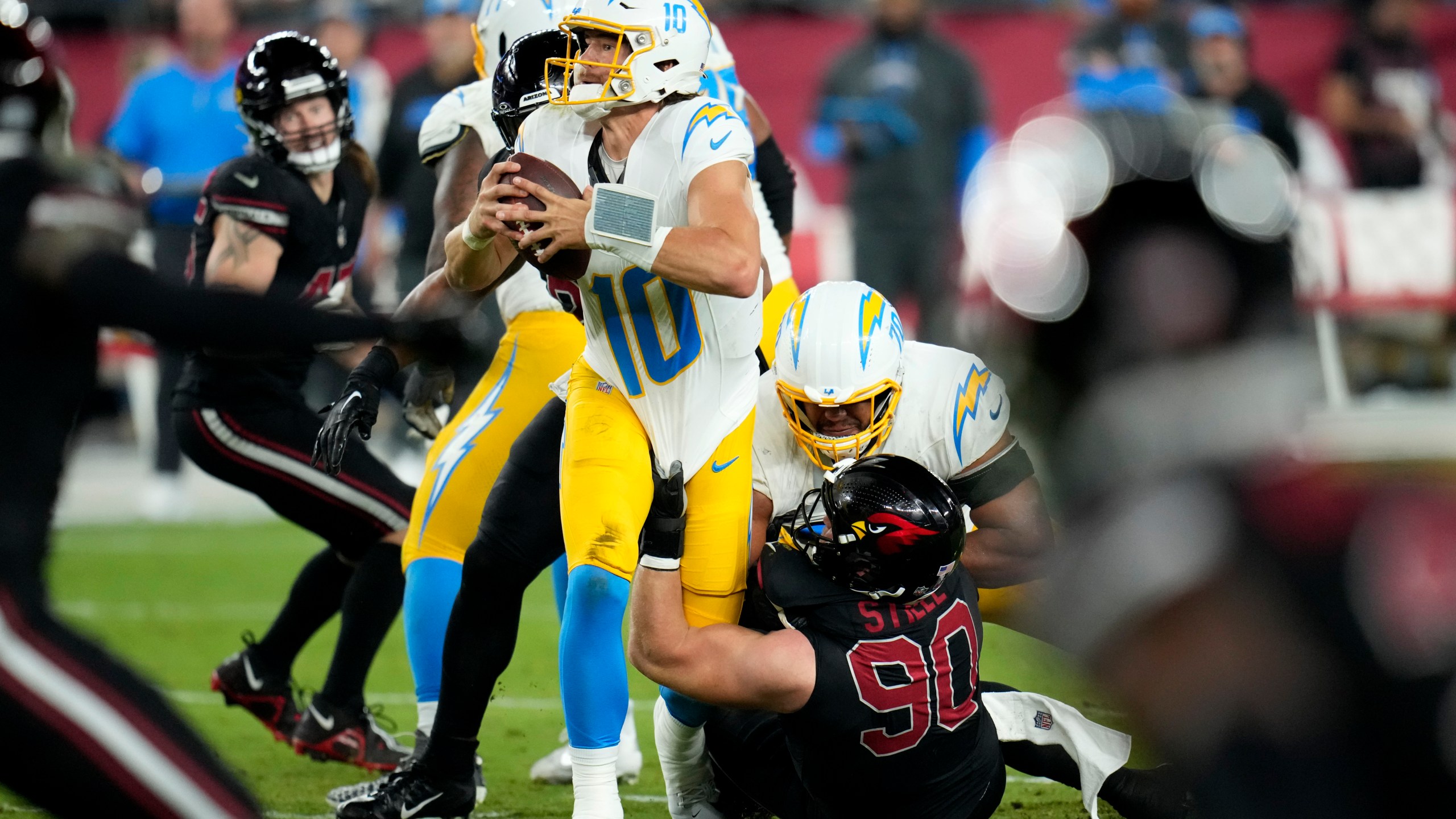 Los Angeles Chargers quarterback Justin Herbert (10) is sacked by Arizona Cardinals defensive end Ben Stille (90) during the first half of an NFL football game, Monday, Oct. 21, 2024, in Glendale Ariz. (AP Photo/Ross D. Franklin)