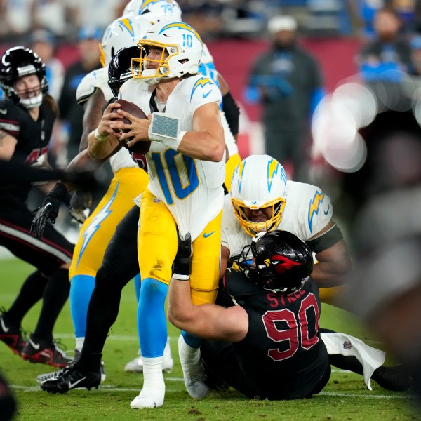 Los Angeles Chargers quarterback Justin Herbert (10) is sacked by Arizona Cardinals defensive end Ben Stille (90) during the first half of an NFL football game, Monday, Oct. 21, 2024, in Glendale Ariz. (AP Photo/Ross D. Franklin)