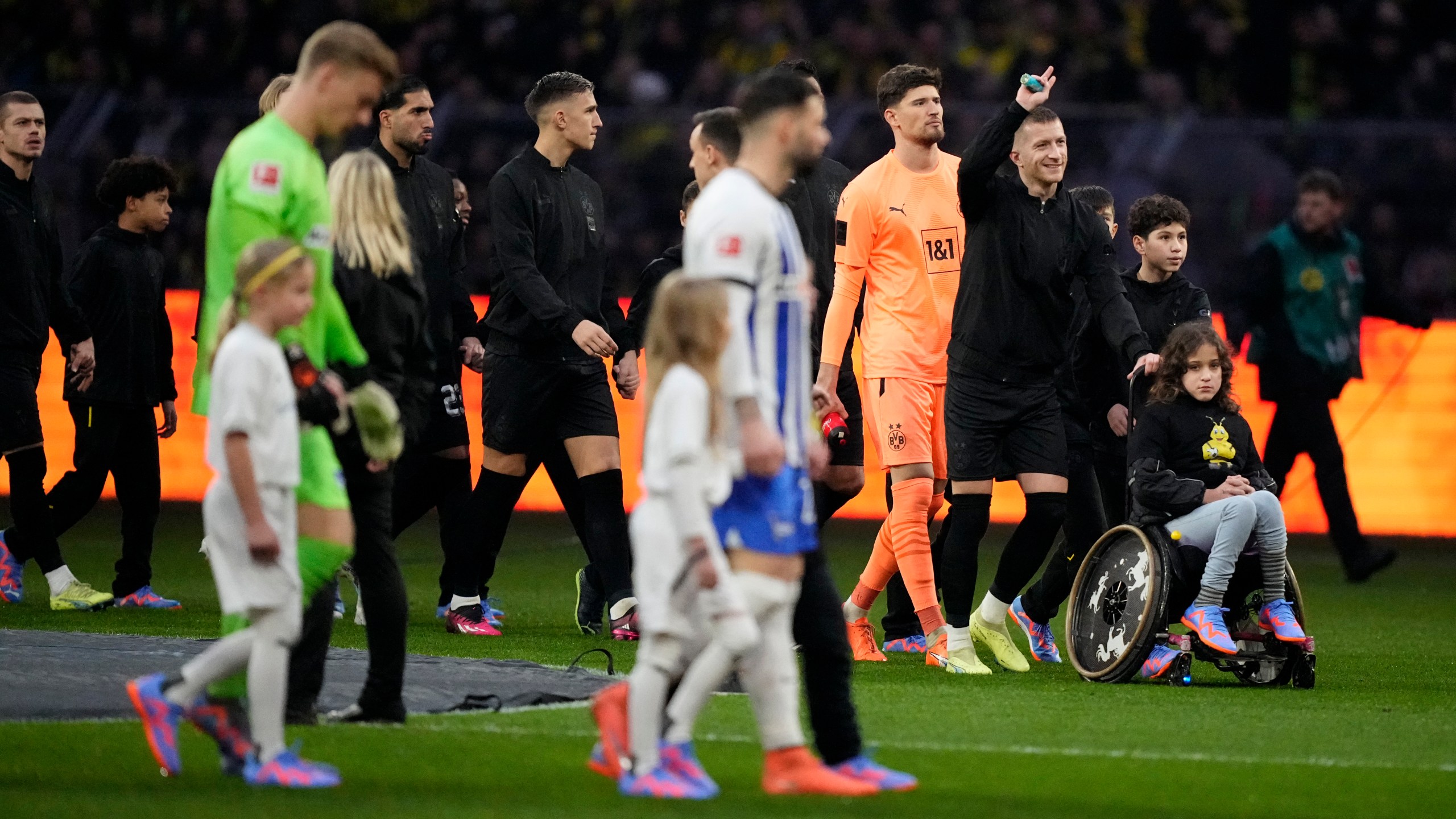 FILE - Dortmund's captain Marco Reus, second right, gestures as he walks into the field with a girl on a wheelchair prior to the start of the German Bundesliga soccer match between Borussia Dortmund and Hertha BSC Berlin at the Westfalenstadion stadium in Dortmund, Germany, Sunday, Feb. 19, 2023. (AP Photo/Martin Meissner, File)