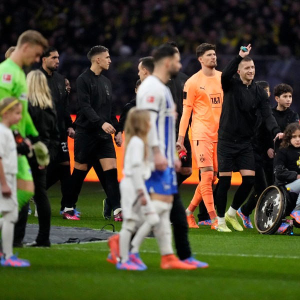 FILE - Dortmund's captain Marco Reus, second right, gestures as he walks into the field with a girl on a wheelchair prior to the start of the German Bundesliga soccer match between Borussia Dortmund and Hertha BSC Berlin at the Westfalenstadion stadium in Dortmund, Germany, Sunday, Feb. 19, 2023. (AP Photo/Martin Meissner, File)