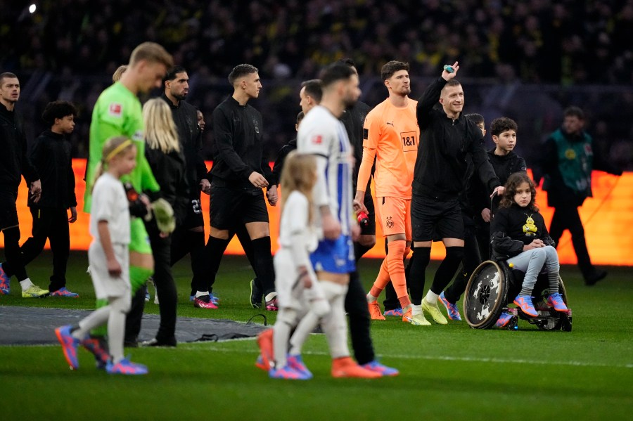 FILE - Dortmund's captain Marco Reus, second right, gestures as he walks into the field with a girl on a wheelchair prior to the start of the German Bundesliga soccer match between Borussia Dortmund and Hertha BSC Berlin at the Westfalenstadion stadium in Dortmund, Germany, Sunday, Feb. 19, 2023. (AP Photo/Martin Meissner, File)