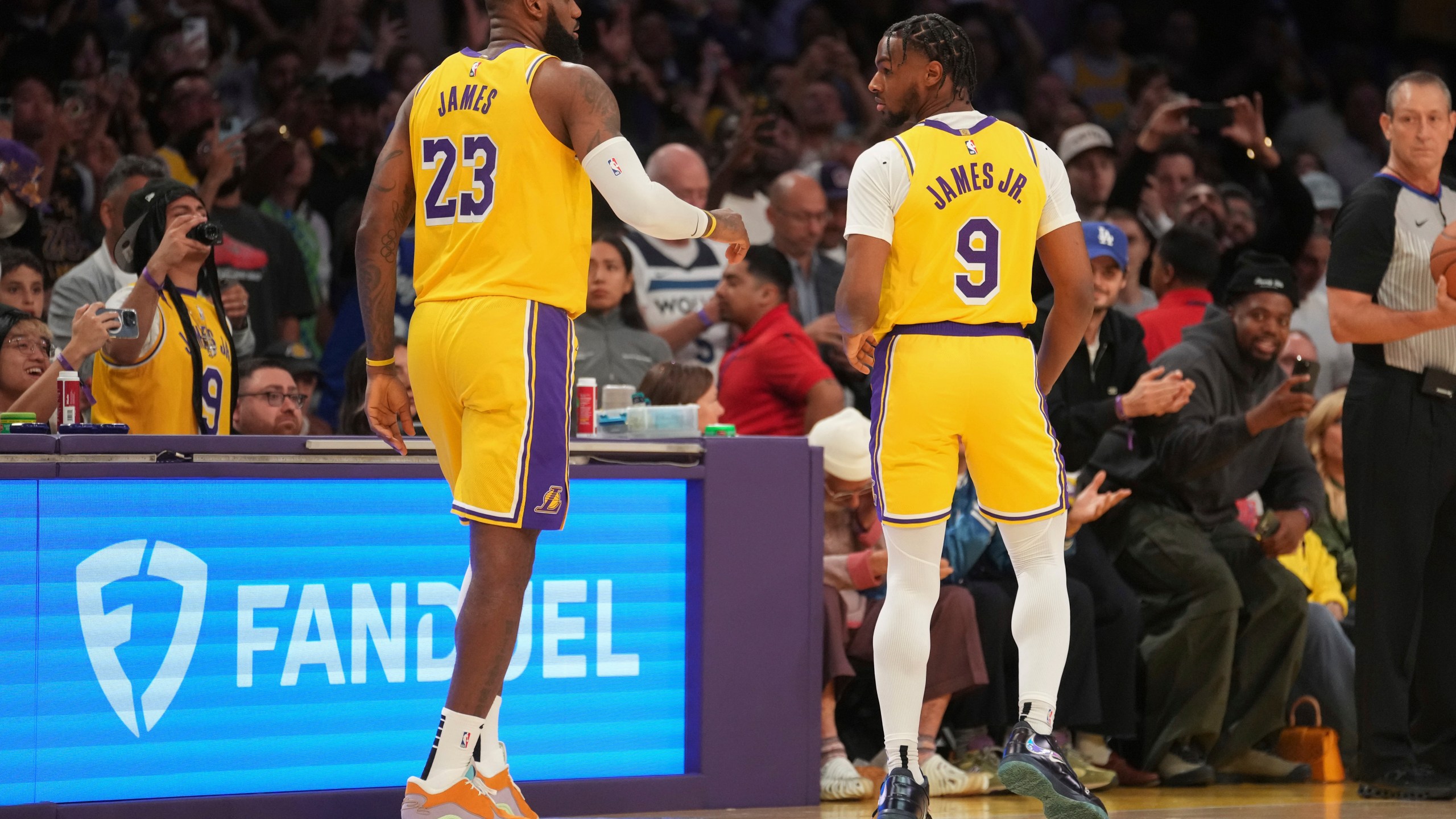 Los Angeles Lakers forward LeBron James (23) and guard Bronny James (9) stand on the court during the first half of an NBA basketball game against the Minnesota Timberwolves, Tuesday, Oct. 22, 2024, in Los Angeles. (AP Photo/Eric Thayer)