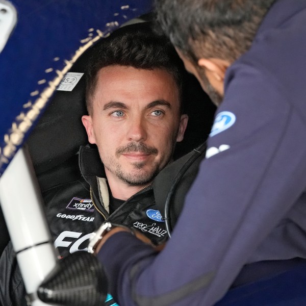 FILE - Race car driver and actor Frankie Muniz, left, talks to a crew member before a practice run, Feb. 16, 2024, at Daytona International Speedway in Daytona Beach, Fla. (AP Photo/Chris O'Meara, File)