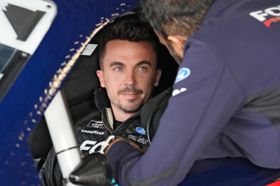 FILE - Race car driver and actor Frankie Muniz, left, talks to a crew member before a practice run, Feb. 16, 2024, at Daytona International Speedway in Daytona Beach, Fla. (AP Photo/Chris O'Meara, File)