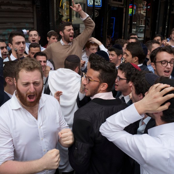 FILE - Jewish men celebrate Simchat Torah on a New York street, Friday, Oct. 13, 2017. The holiday marks the conclusion of the annual cycle of public Torah readings. (AP Photo/Mark Lennihan, File)