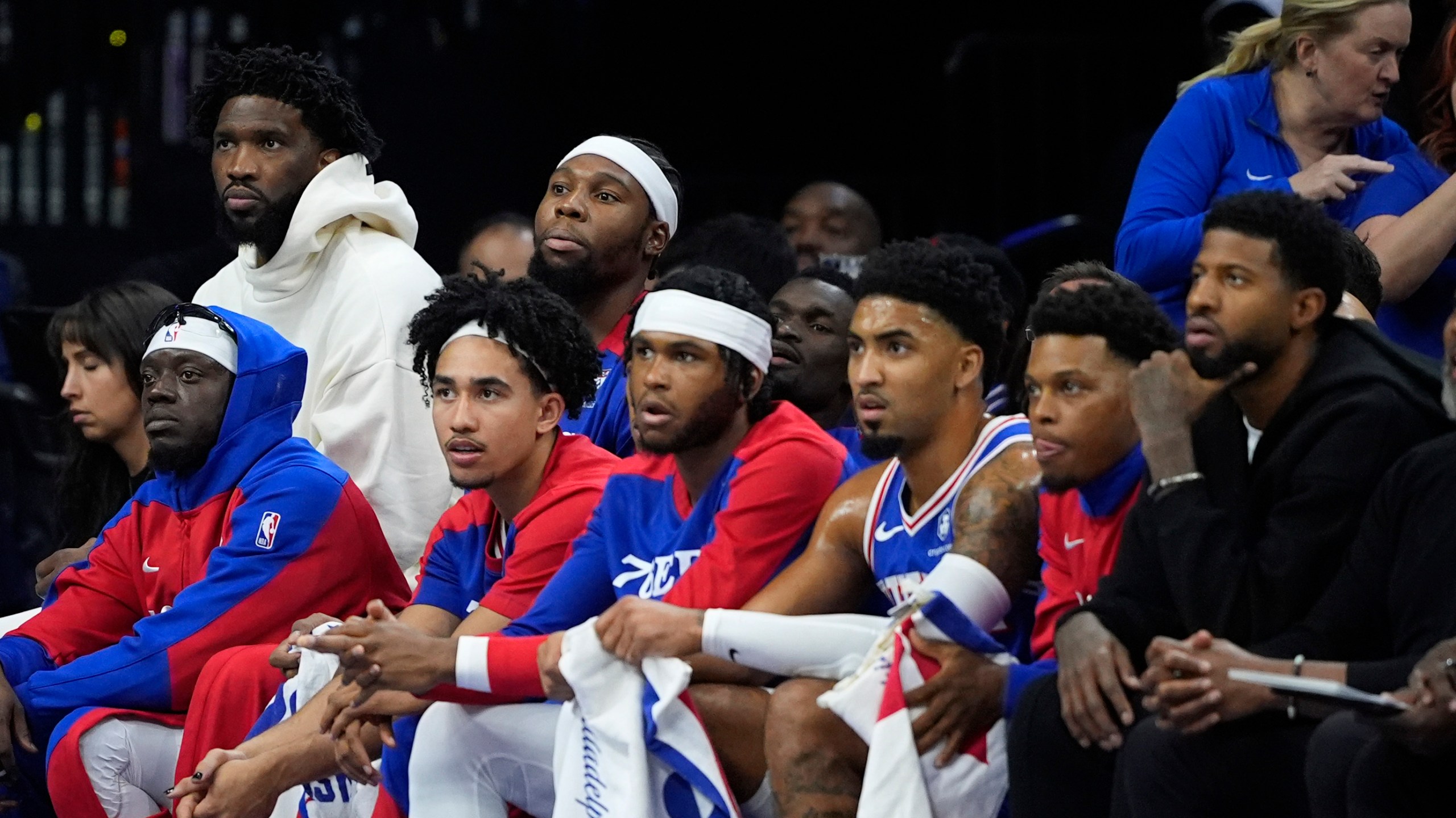 Philadelphia 76ers' Joel Embiid, top left, and Paul George, bottom right, watch from the bench during the first half of an NBA basketball game against the Milwaukee Bucks, Wednesday, Oct. 23, 2024, in Philadelphia. (AP Photo/Matt Slocum)