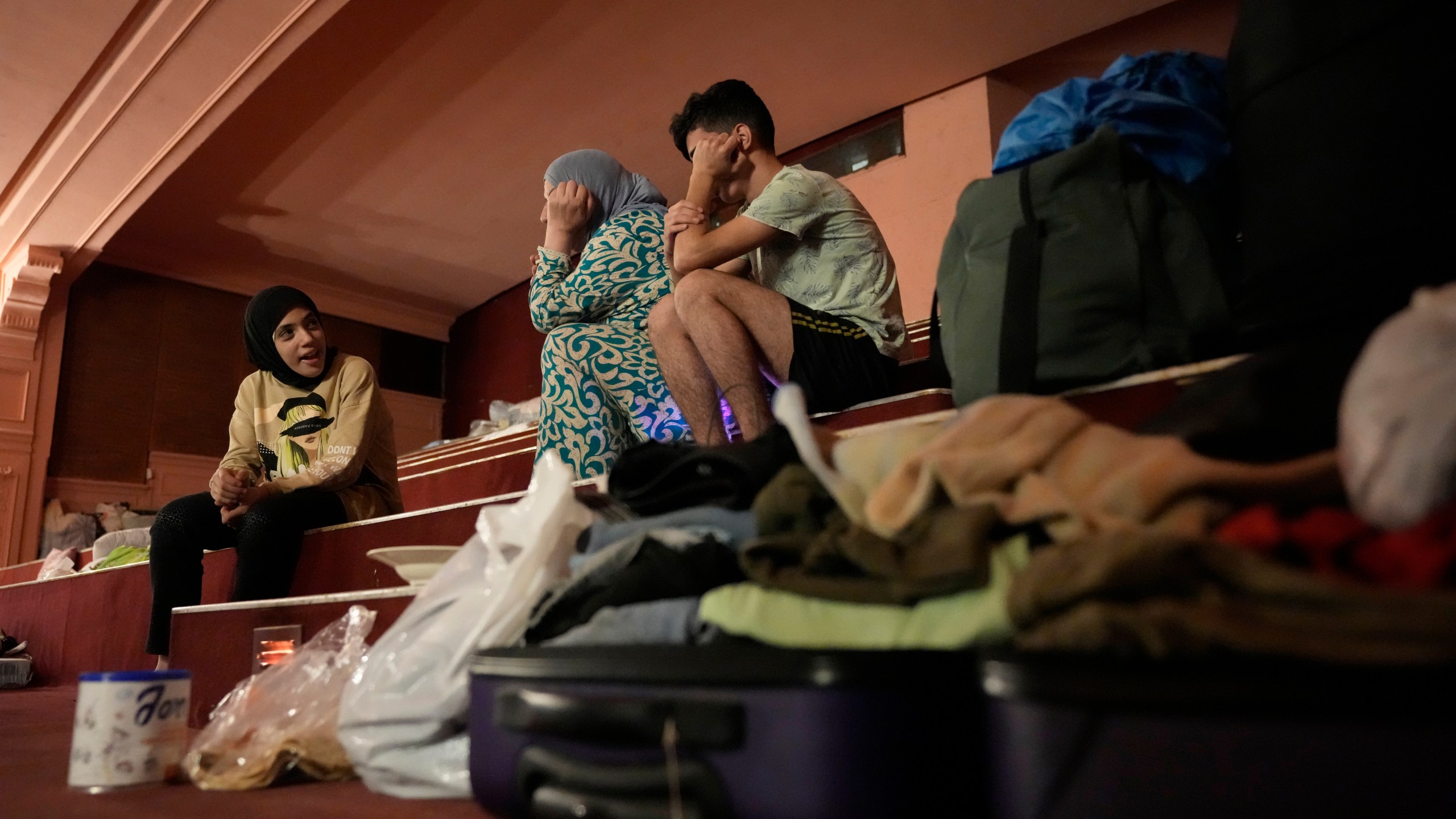 Mona Hanafi, center, who fled the ongoing Hezbollah-Israel war in south Lebanon, sits with her family, inside one of Beirut's oldest and best known movie theatres, Le Colisee, in Beirut, Lebanon, Tuesday, Oct. 22, 2024. (AP Photo/Hussein Malla)