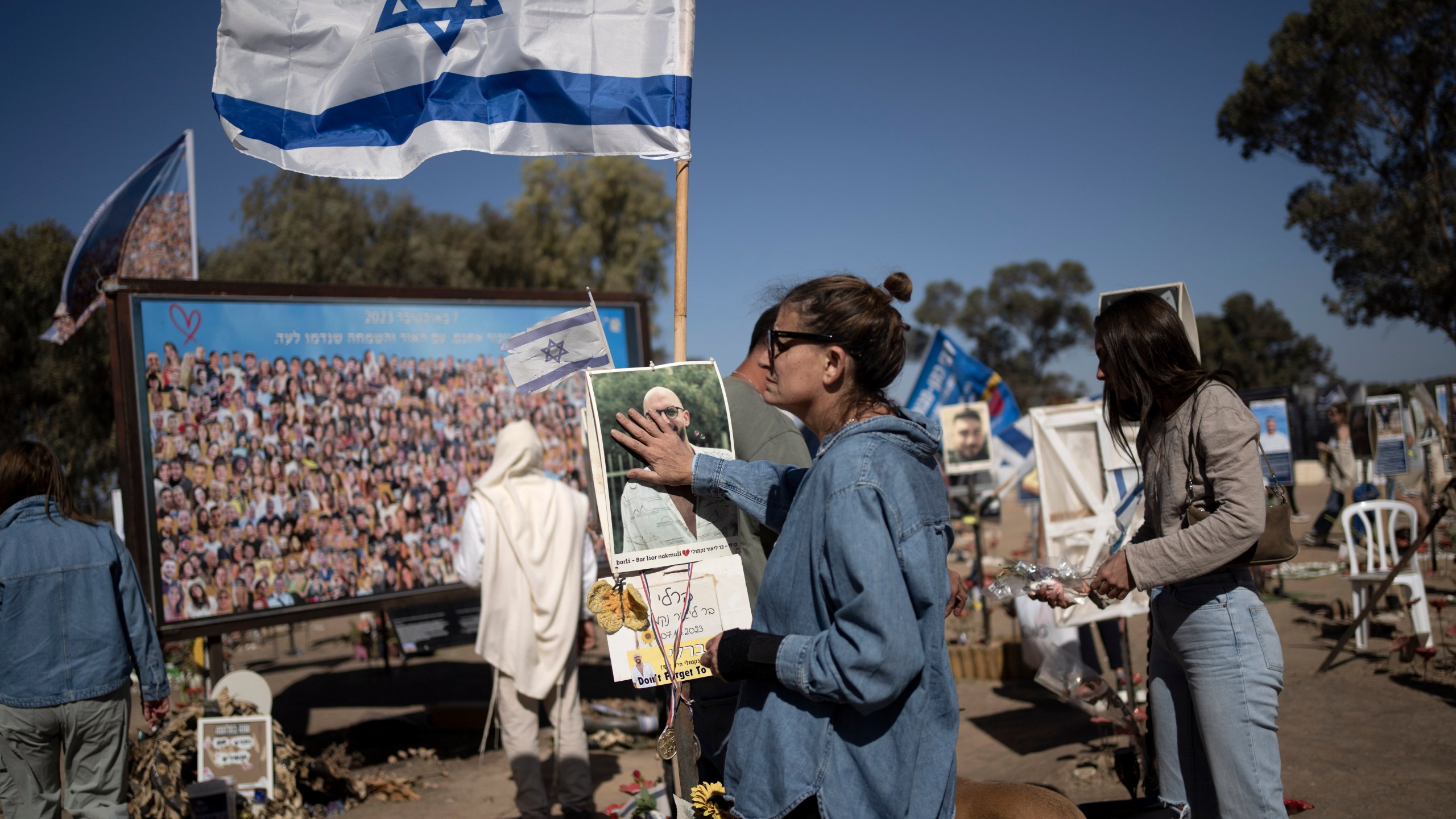 A woman pauses to touch the memorial marker of her loved one, Bar Lior Nakmuli, at the site of the Nova music festival, where hundreds of revelers were killed or kidnapped by Hamas, on the Jewish holiday of Simchat Torah, marking one year in the Hebrew calendar since the attack, near Kibbutz Re'im, southern Israel near the Gaza Strip, Thursday, Oct. 24, 2024. (AP Photo/Maya Alleruzzo)