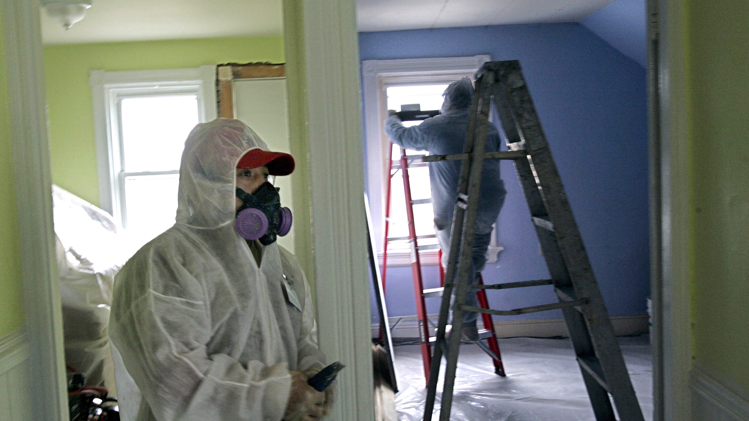 FILE - Contractors Luis Benitez, foreground, and Jose Diaz, background, clean up lead paint in a contaminated building, Feb. 23, 2006, in Providence, R.I. (AP Photo/Chitose Suzuki)