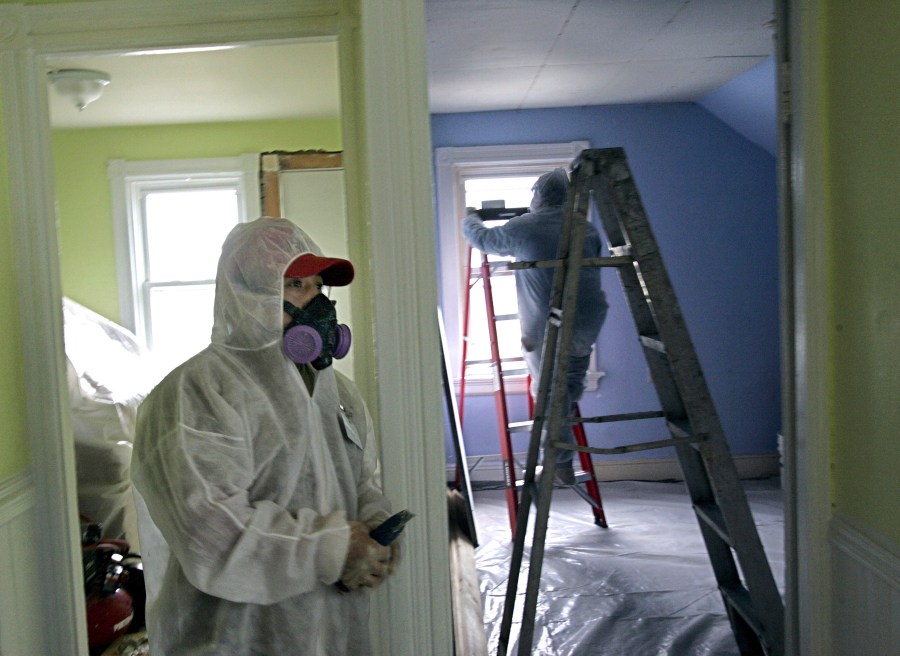 FILE - Contractors Luis Benitez, foreground, and Jose Diaz, background, clean up lead paint in a contaminated building, Feb. 23, 2006, in Providence, R.I. (AP Photo/Chitose Suzuki)