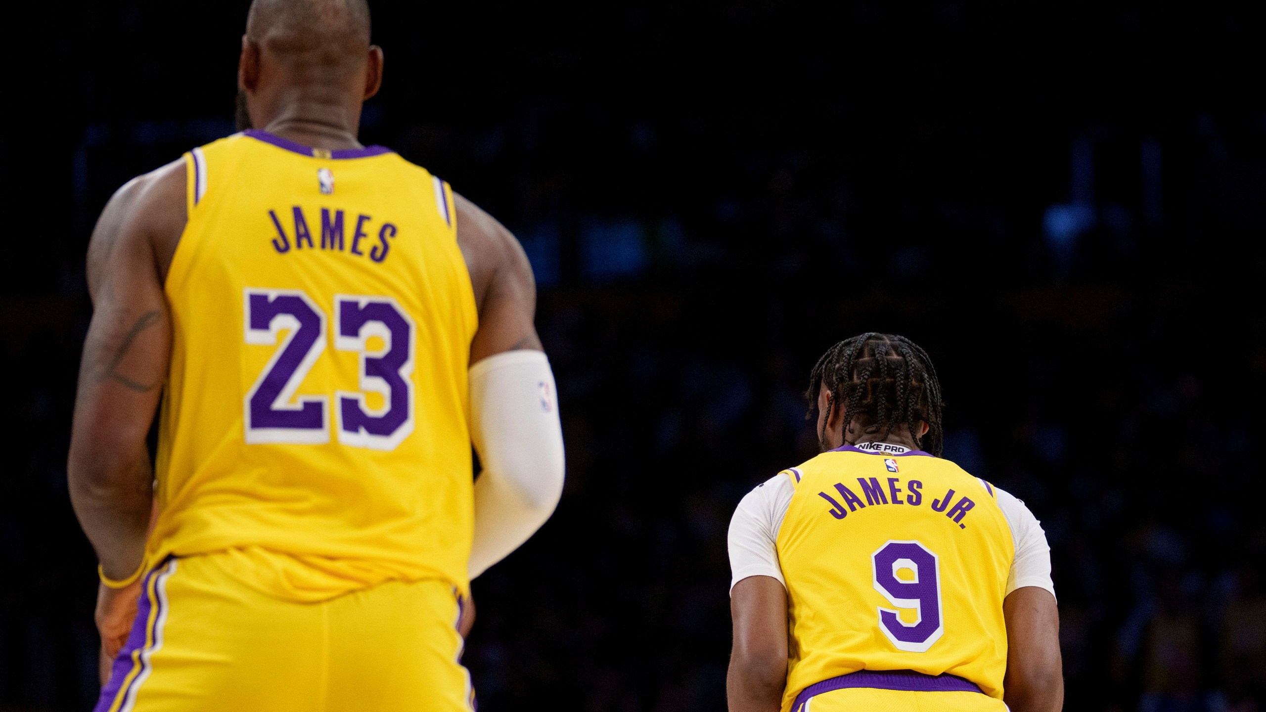 Los Angeles Lakers forward LeBron James (23) and guard Bronny James (9) stand on the court during the first half of an NBA basketball game against the Minnesota Timberwolves, Tuesday, Oct. 22, 2024, in Los Angeles. (AP Photo/Eric Thayer)