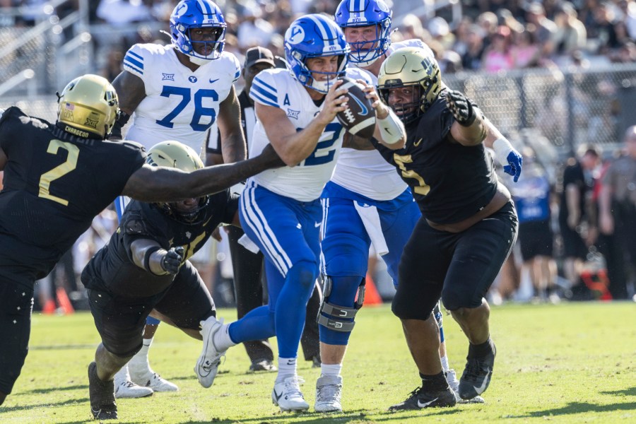 BYU quarterback Jake Retzlaff, Center, is sacked by Central Florida's defense during the first half of an NCAA college football game, Saturday, Oct. 26, 2024, in Orlando, Fla. (AP Photo/Kevin Kolczynski)