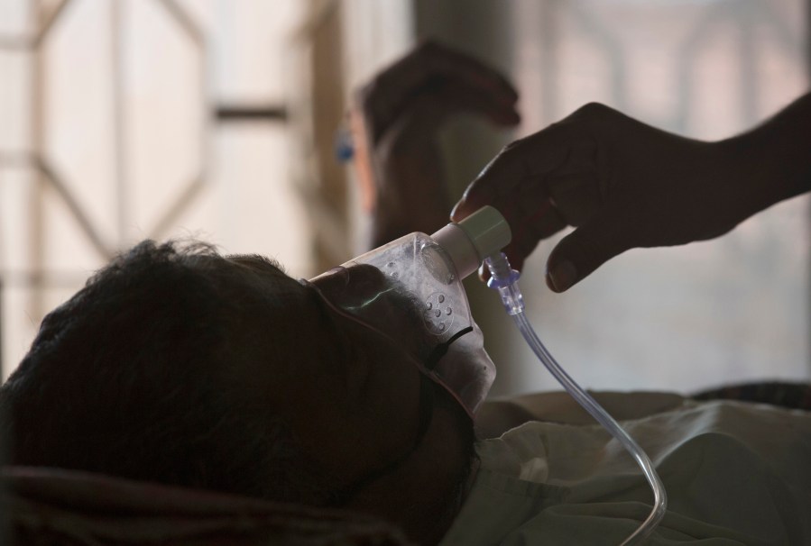 FILE - A relative adjusts the oxygen mask of a tuberculosis patient at a TB hospital on World Tuberculosis Day in Hyderabad, India, March 24, 2018. (AP Photo/Mahesh Kumar A., File)