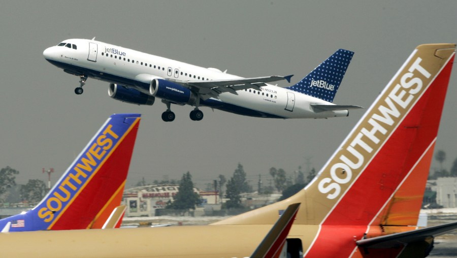 FILE - A JetBlue Airbus flies over a pair of Southwest Airlines' jets from Bob Hope Airport in Burbank, Calif., bound for New York's JFK airport, July 19, 2005. (AP Photo/Reed Saxon, File)