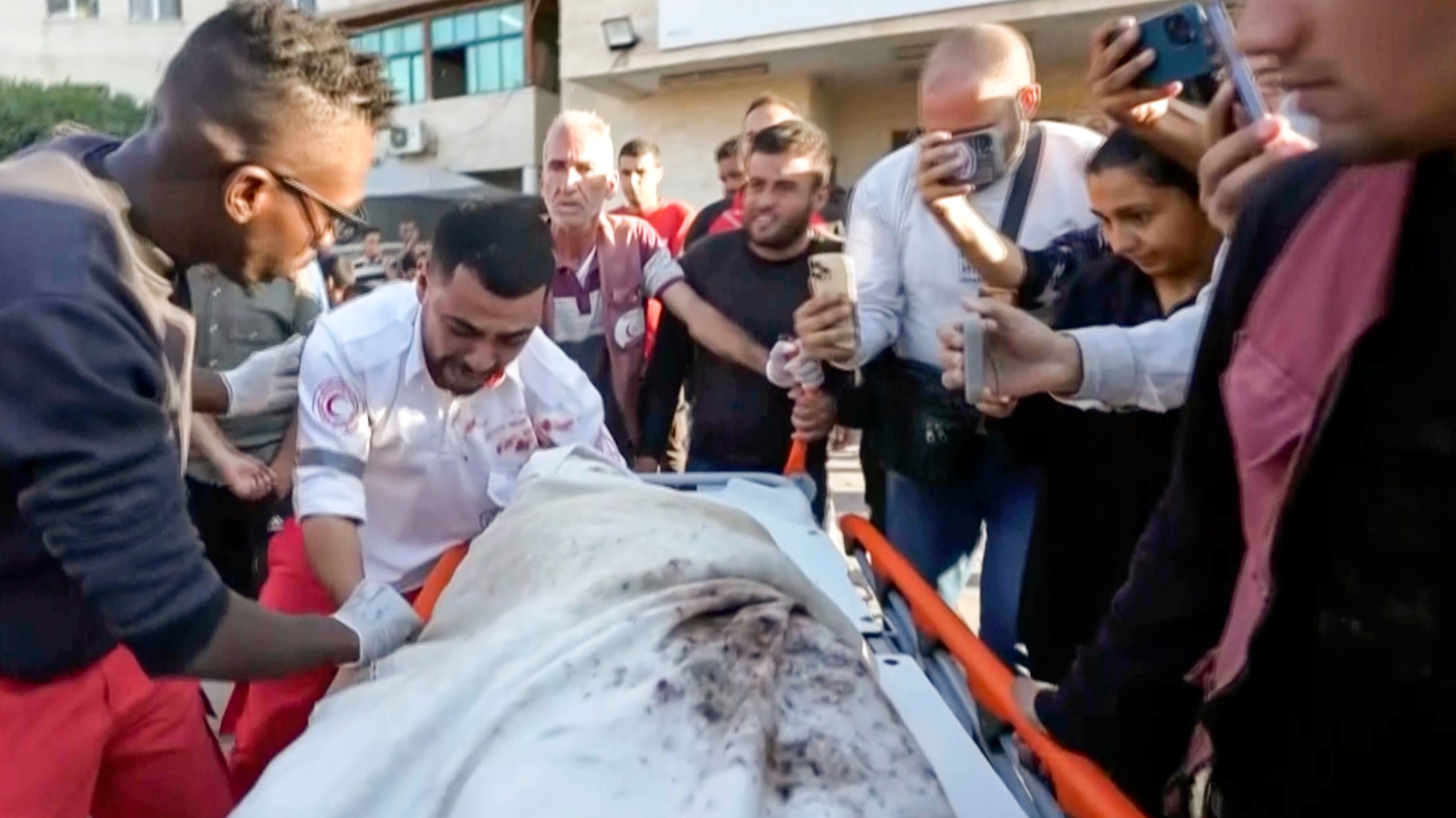 In this image made from an Associated Press video, medic Abed Al Aziz Bardini cries over the body of his mother after he realizes it's her, shouting in Arabic, "Oh god, I swear she is my mother. I didn't know it was her," on Wednesday, Oct. 30, 2024, in Deir al-Balah on the Gaza Strip. (AP Photo/Abed Al Kareem Hana)