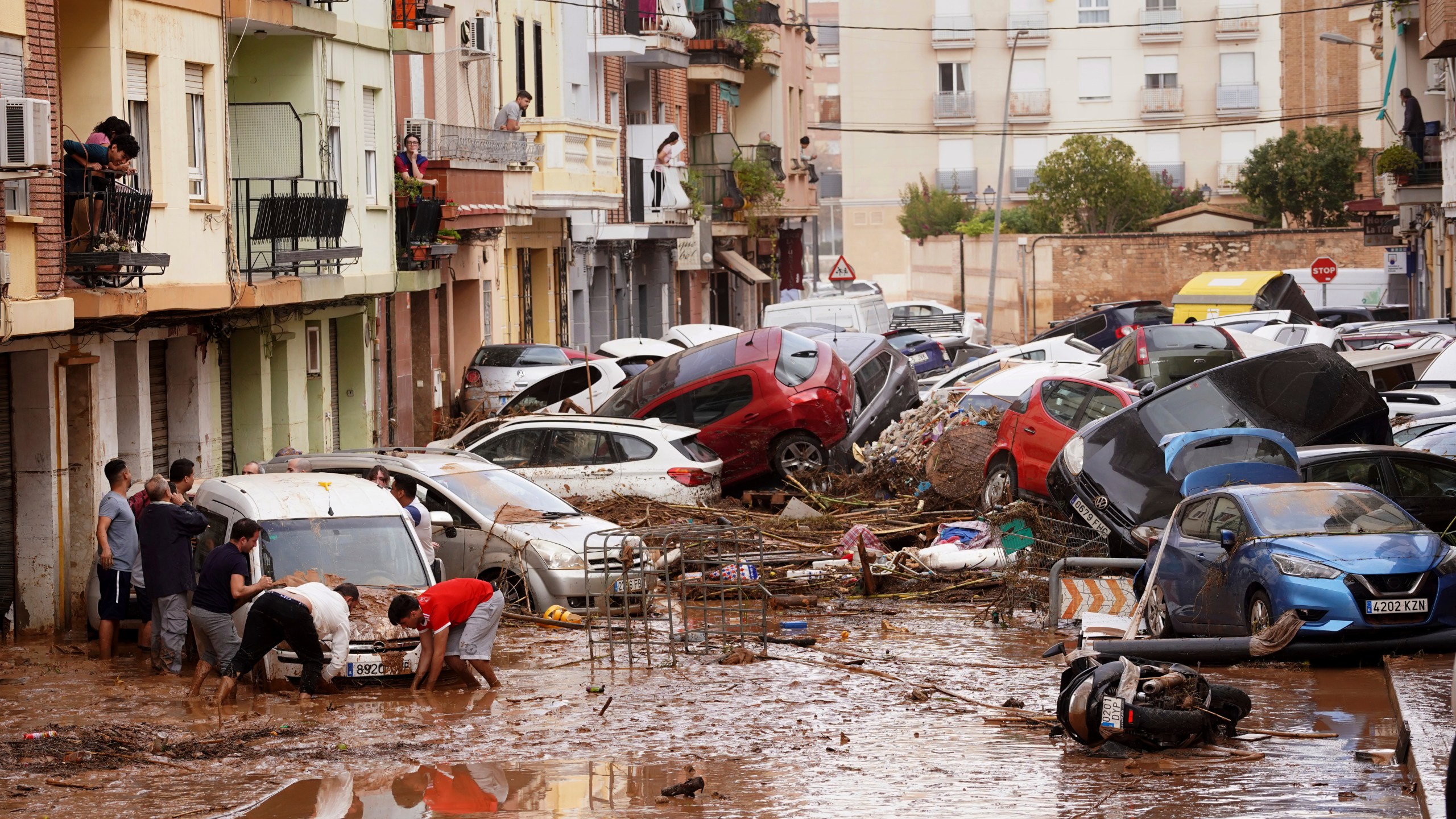 Residents look at cars piled up after being swept away by floods in Valencia, Spain, Wednesday, Oct. 30, 2024. (AP Photo/Alberto Saiz)