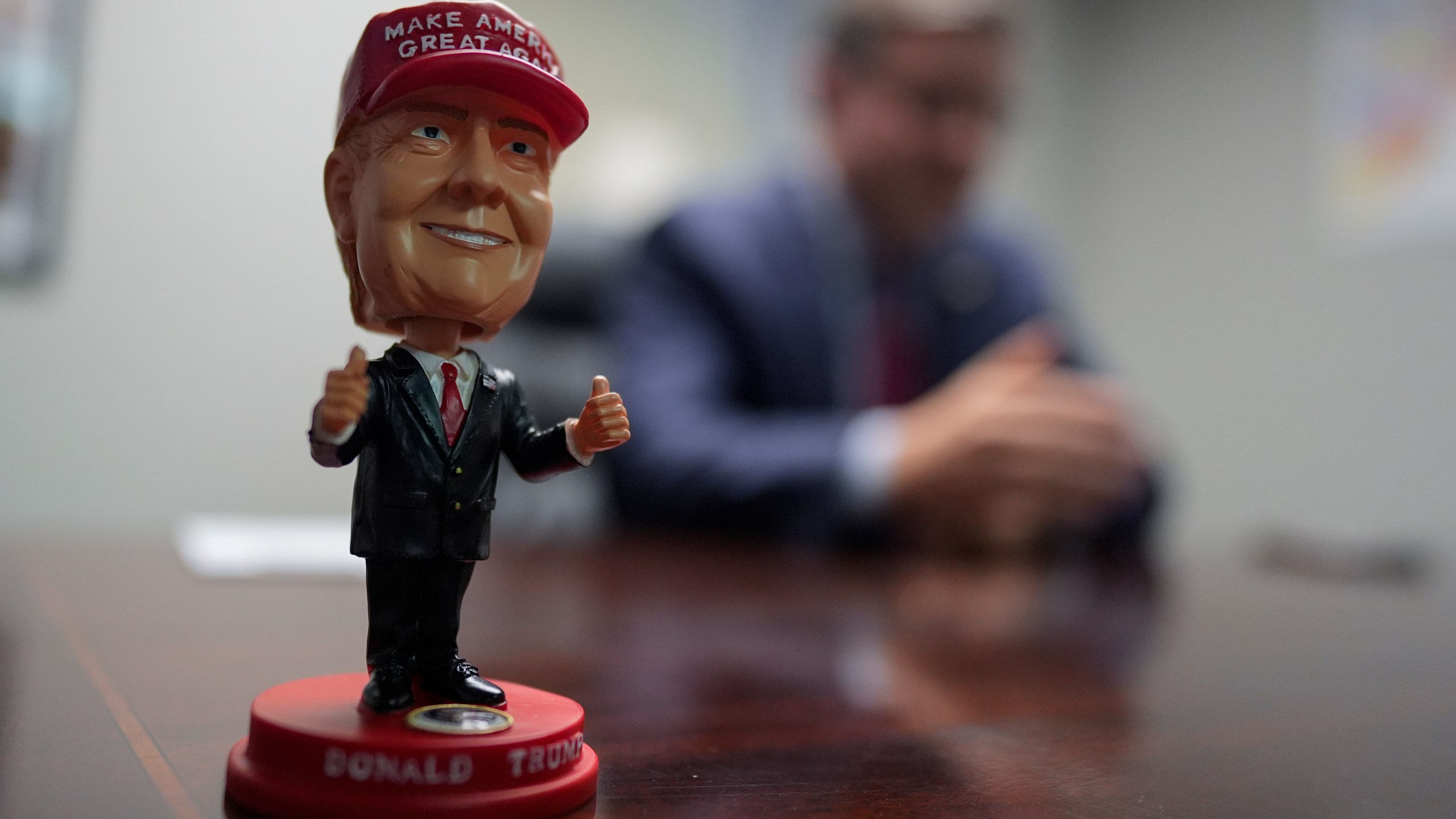 A bobblehead of Republican presidential nominee former President Donald Trump sits on the desk as Speaker of the House Mike Johnson, R-La., speaks during an interview with The Associated Press at the Lucas County Republican Party headquarters in Holland, Ohio, Saturday, Oct. 26, 2024. (AP Photo/Carolyn Kaster)