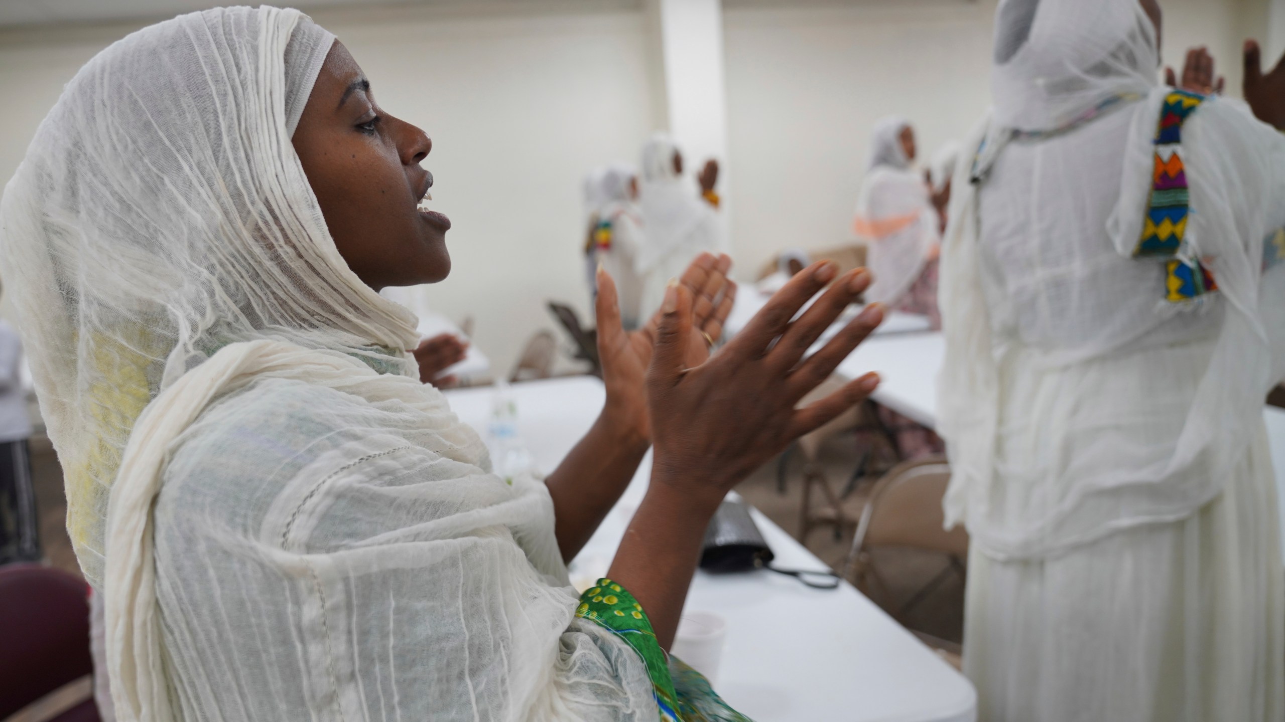 Mintamir Endanew, left, and other members of the Ethiopian Orthodox Tewahedo Church pray after a post-liturgy lunch of pancake-like injera bread on Sunday, Oct. 20, 2024, in Worthington, Minn. (AP Photo/Jessie Wardarski)