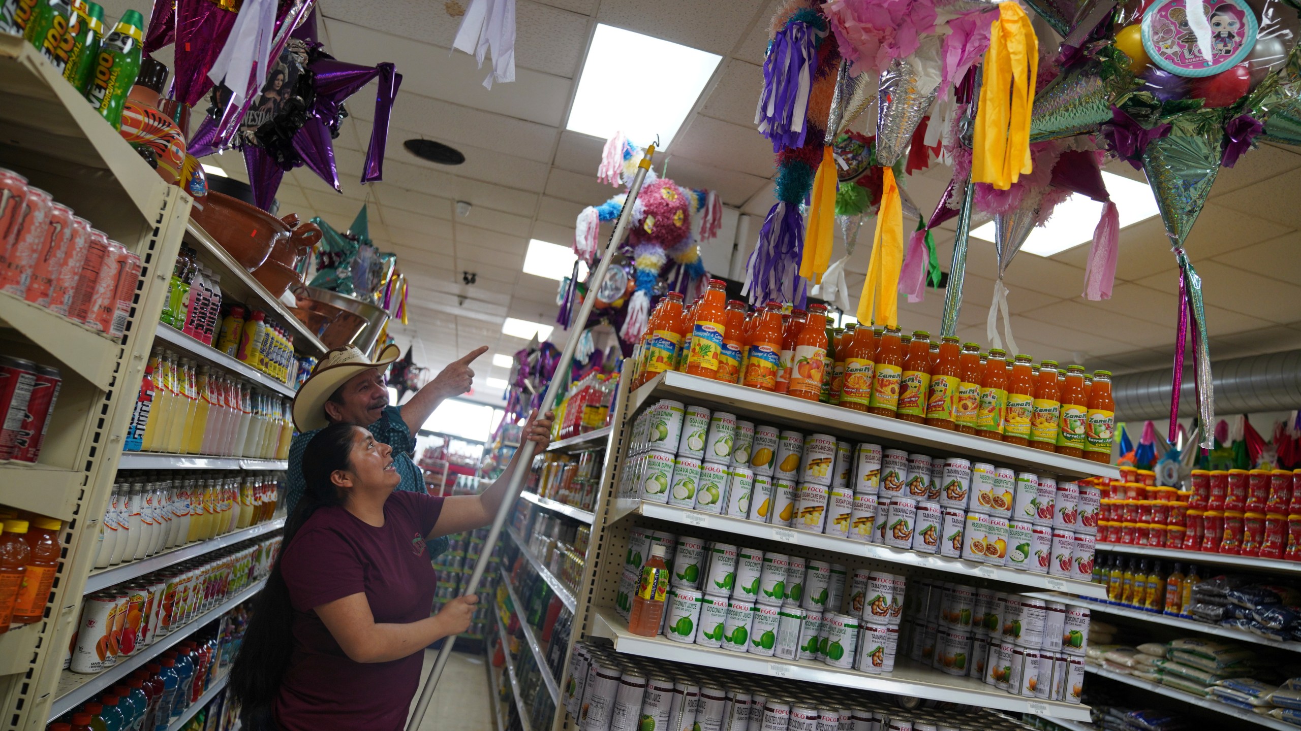 Cristina Cabrera, who fled poverty in Central America three years ago, helps a customer pick a piñata at El Mexicano, a local grocery in downtown Worthington, Minn., on Saturday, Oct. 19, 2024. (AP Photo/Jessie Wardarski)