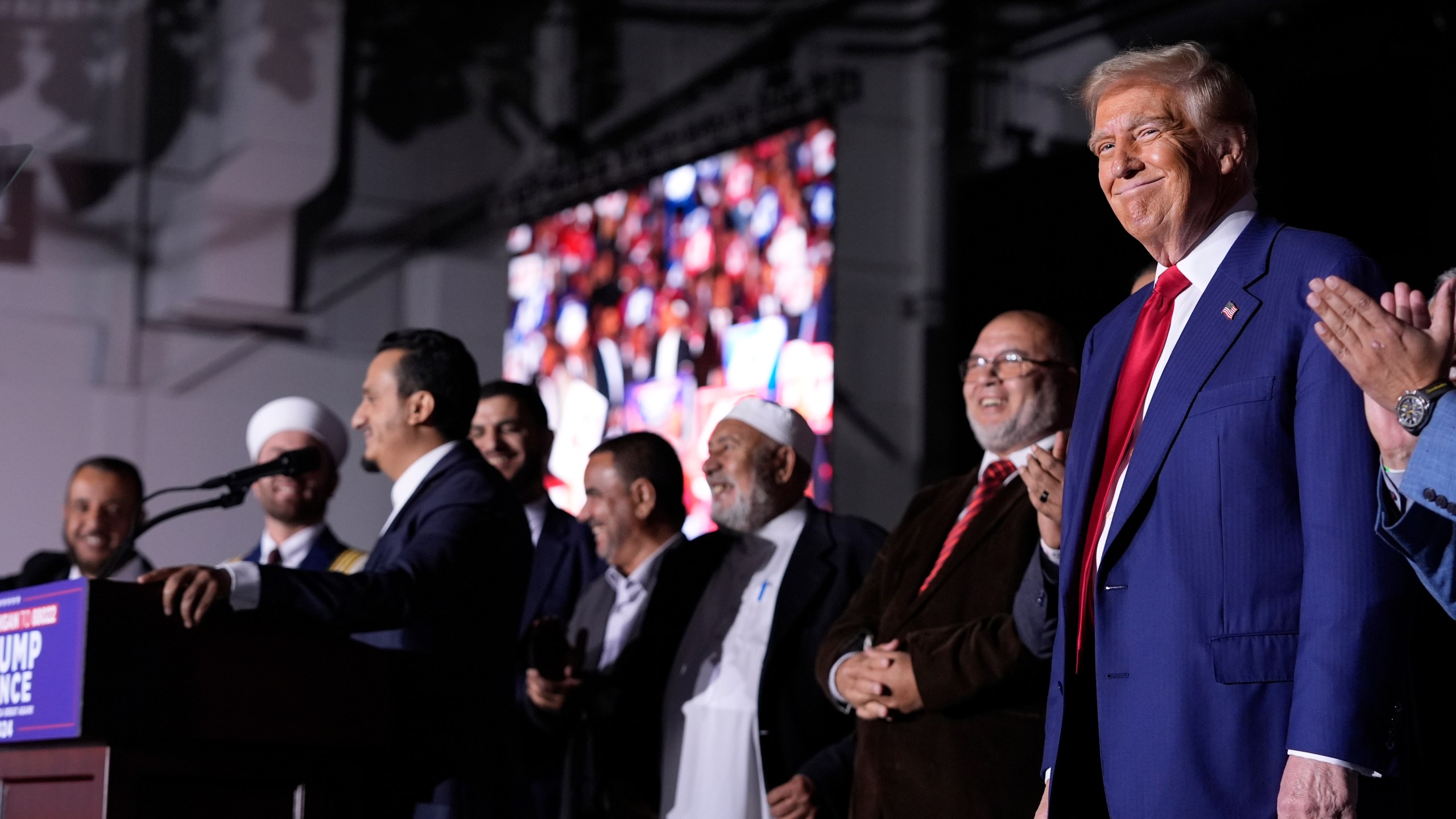 Republican presidential nominee former President Donald Trump, right, looks on as local Muslim leaders speak during a campaign rally at the Suburban Collection Showplace, Saturday, Oct. 26, 2024, in Novi, Mich. (AP Photo/Alex Brandon)