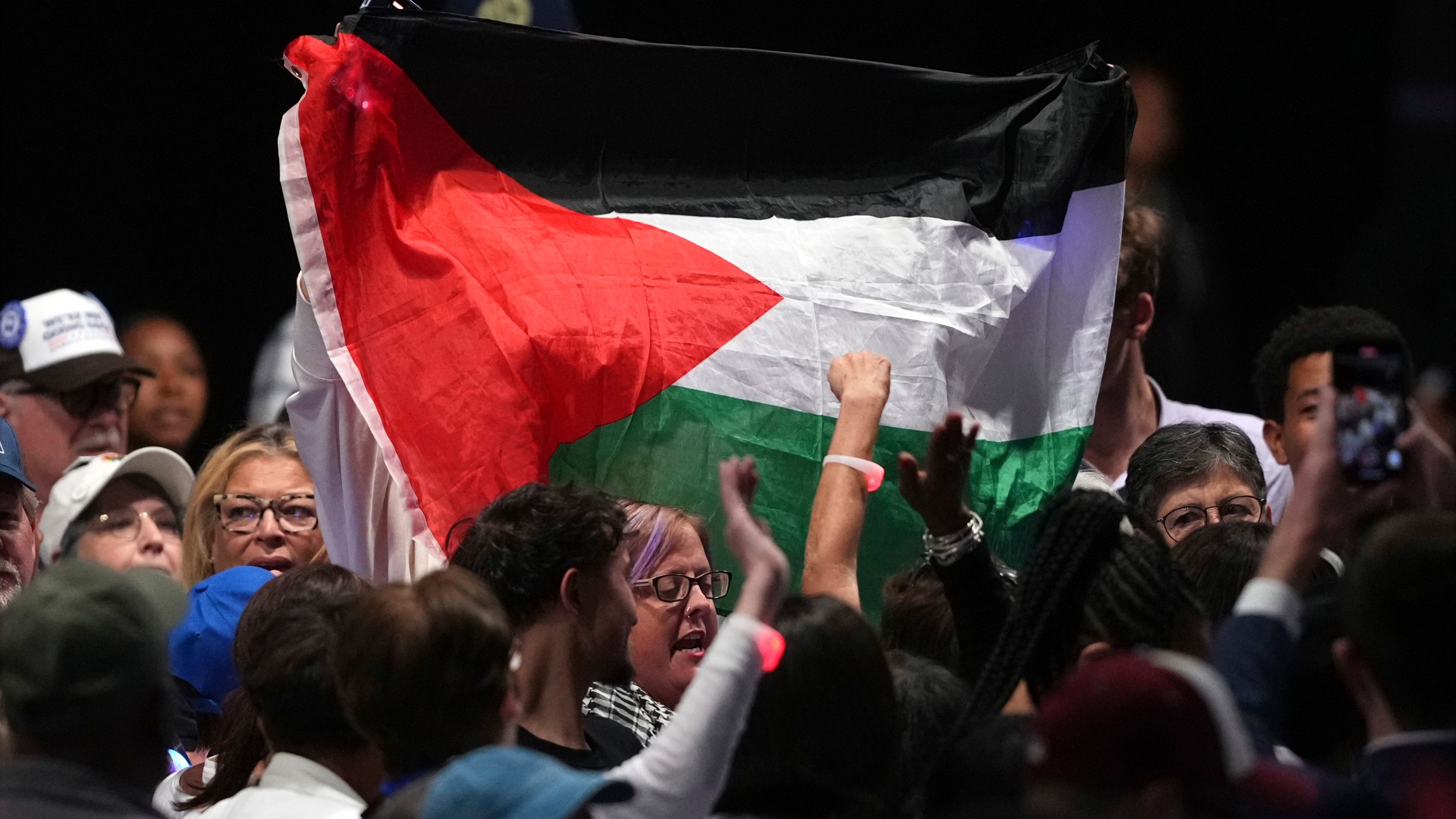 A protesters holds up a Palestinian flag as Democratic presidential nominee Vice President Kamala Harris speaks during a campaign event at the PA Farm Show Complex and Expo Center, Wednesday, Oct. 30, 2024, in Harrisburg, Pa. (AP Photo/Matt Slocum)