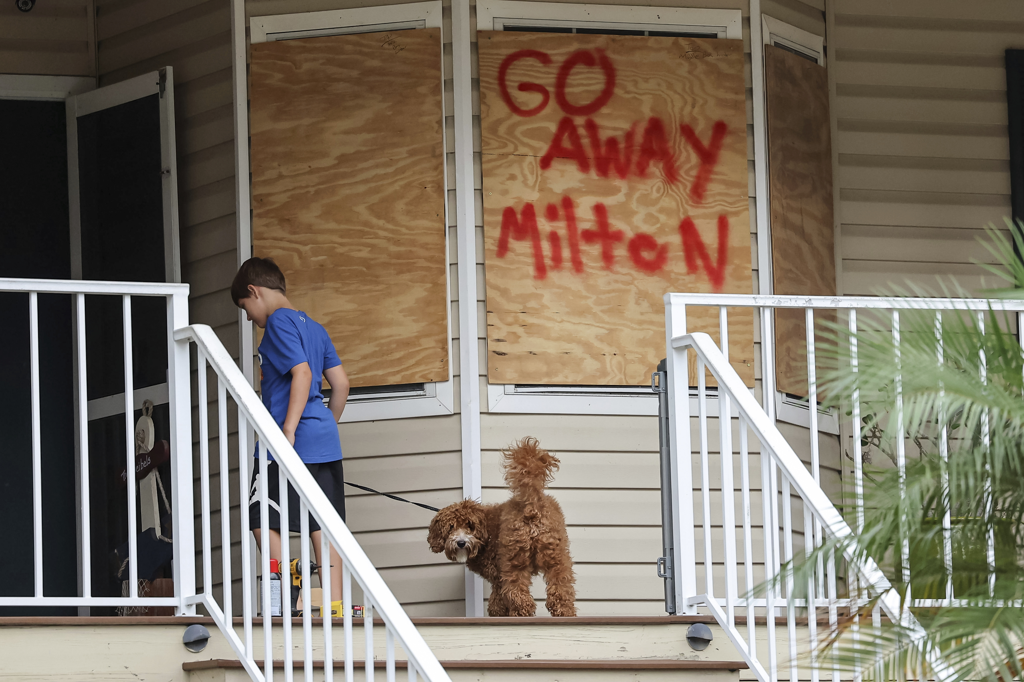 Noah Weibel and his dog Cookie climb the steps to their home as their family prepares for Hurricane Milton on Monday, Oct. 7, 2024, in Port Richey, Fla.